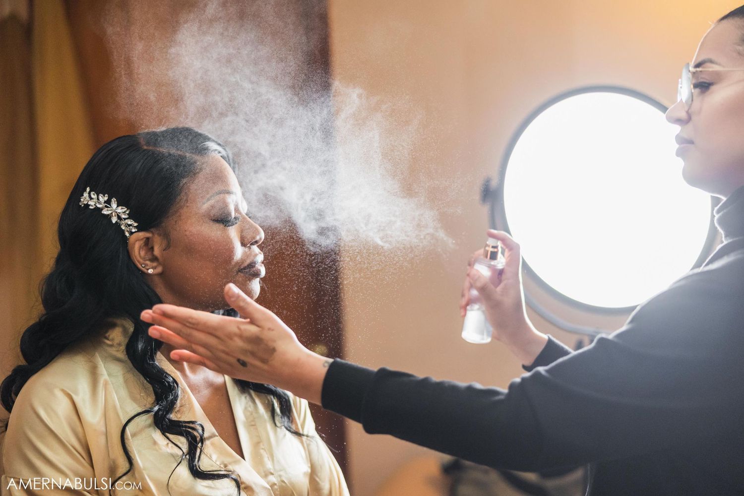 Makeup artist applies finishing touches with a setting spray during bridal preparation.