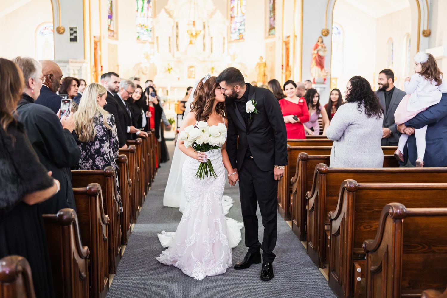 A couple walks down the church aisle as guests look on from wooden pews during their traditional wedding ceremony.
