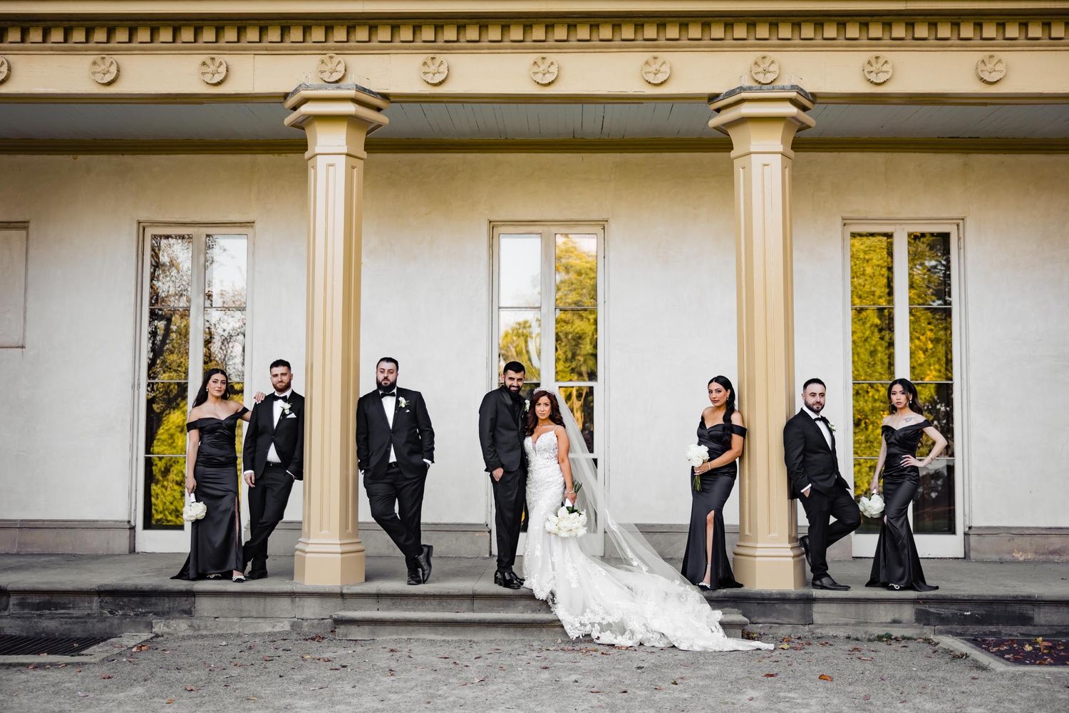 Wedding party poses on steps of classic columned building.
