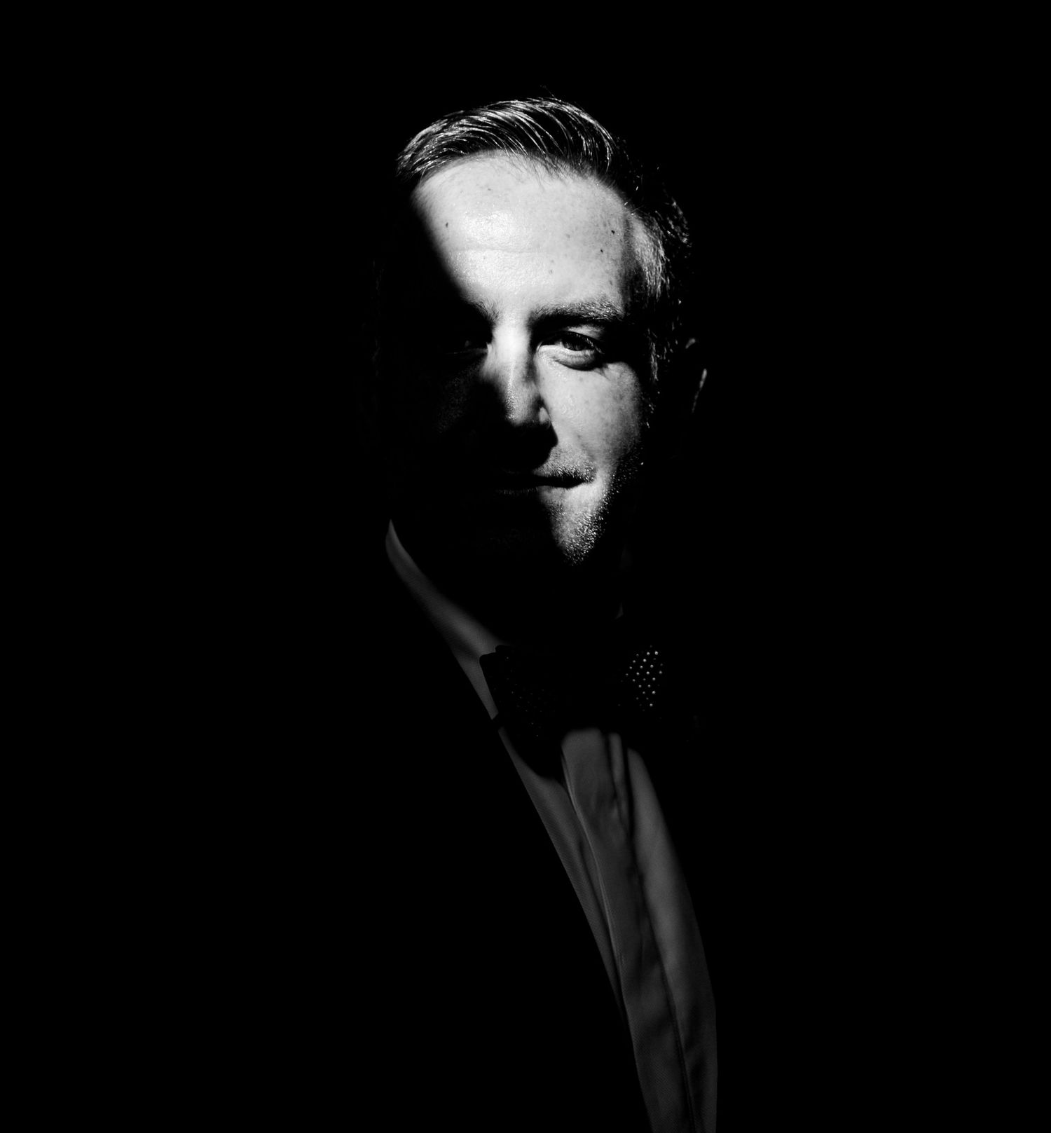 Dramatic black and white profile portrait with moody lighting and shadows.
