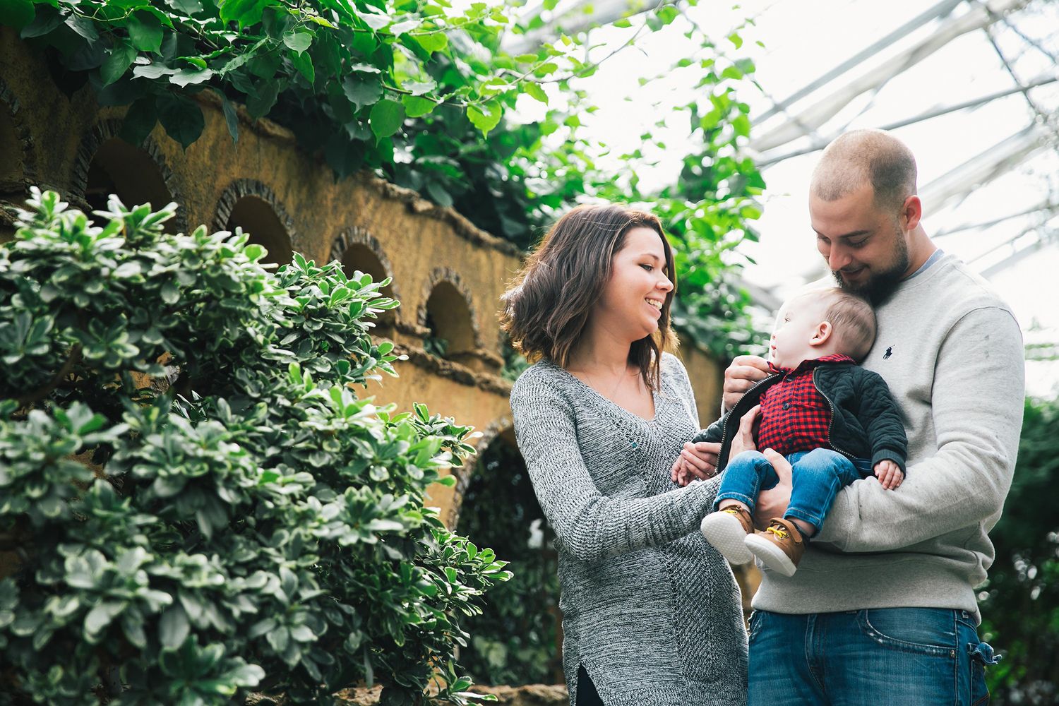 Family enjoying a candid moment together in a garden setting with greenery in the background.