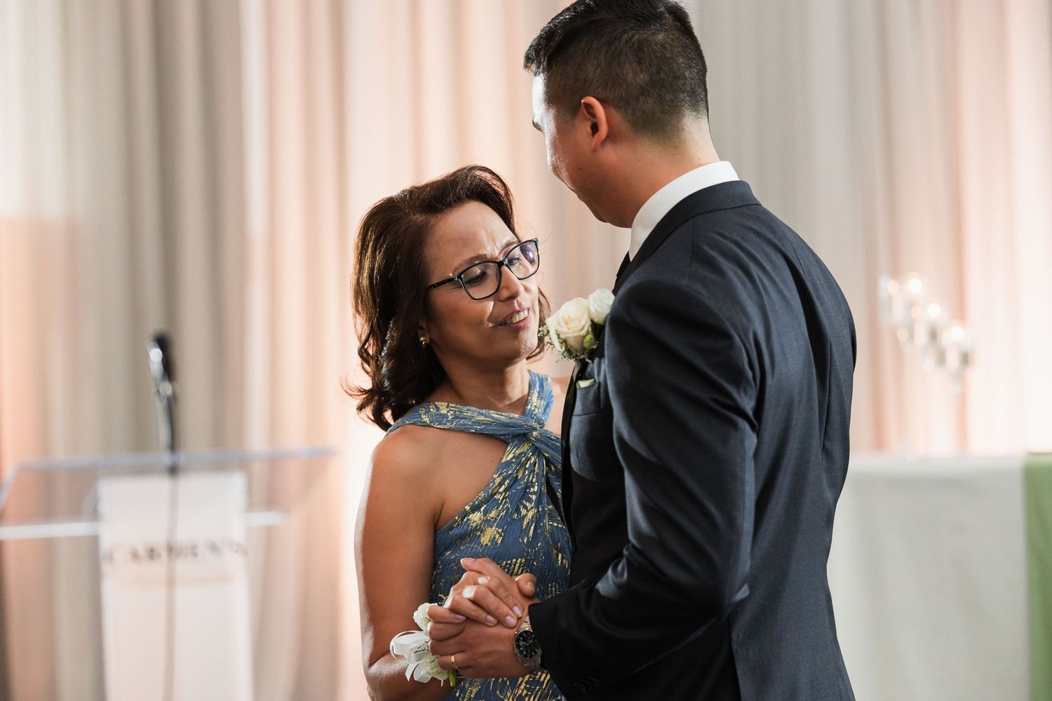 A woman in a blue dress and a man in a suit share a dance at a formal event.