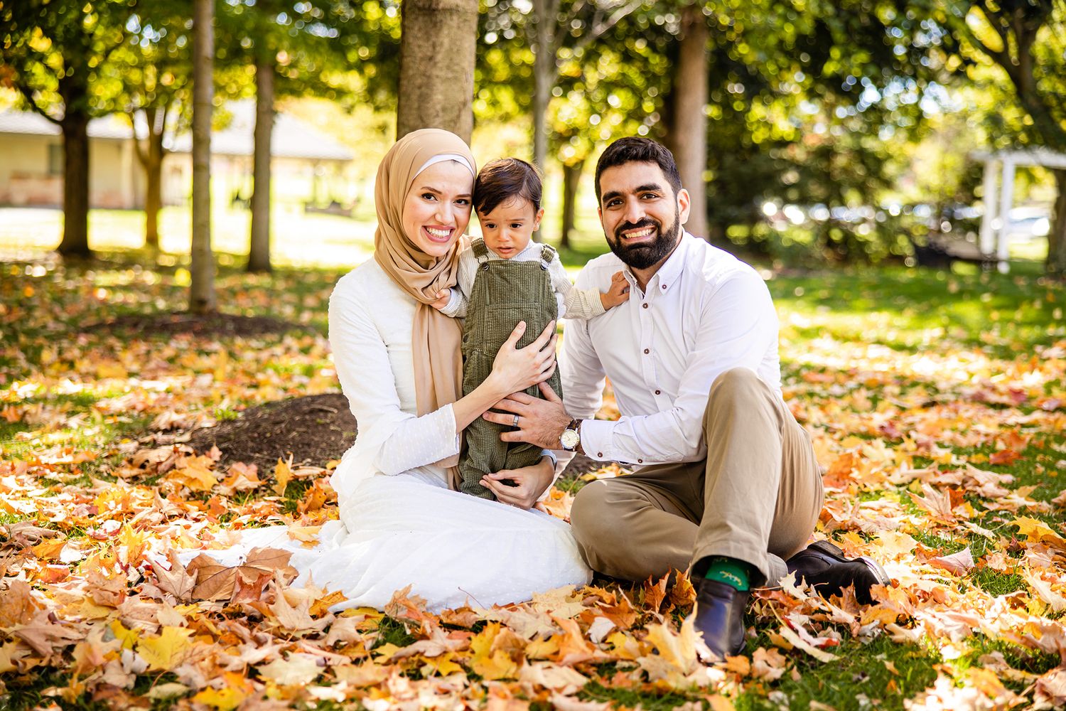 Family playing in fallen autumn leaves during outdoor photo session.