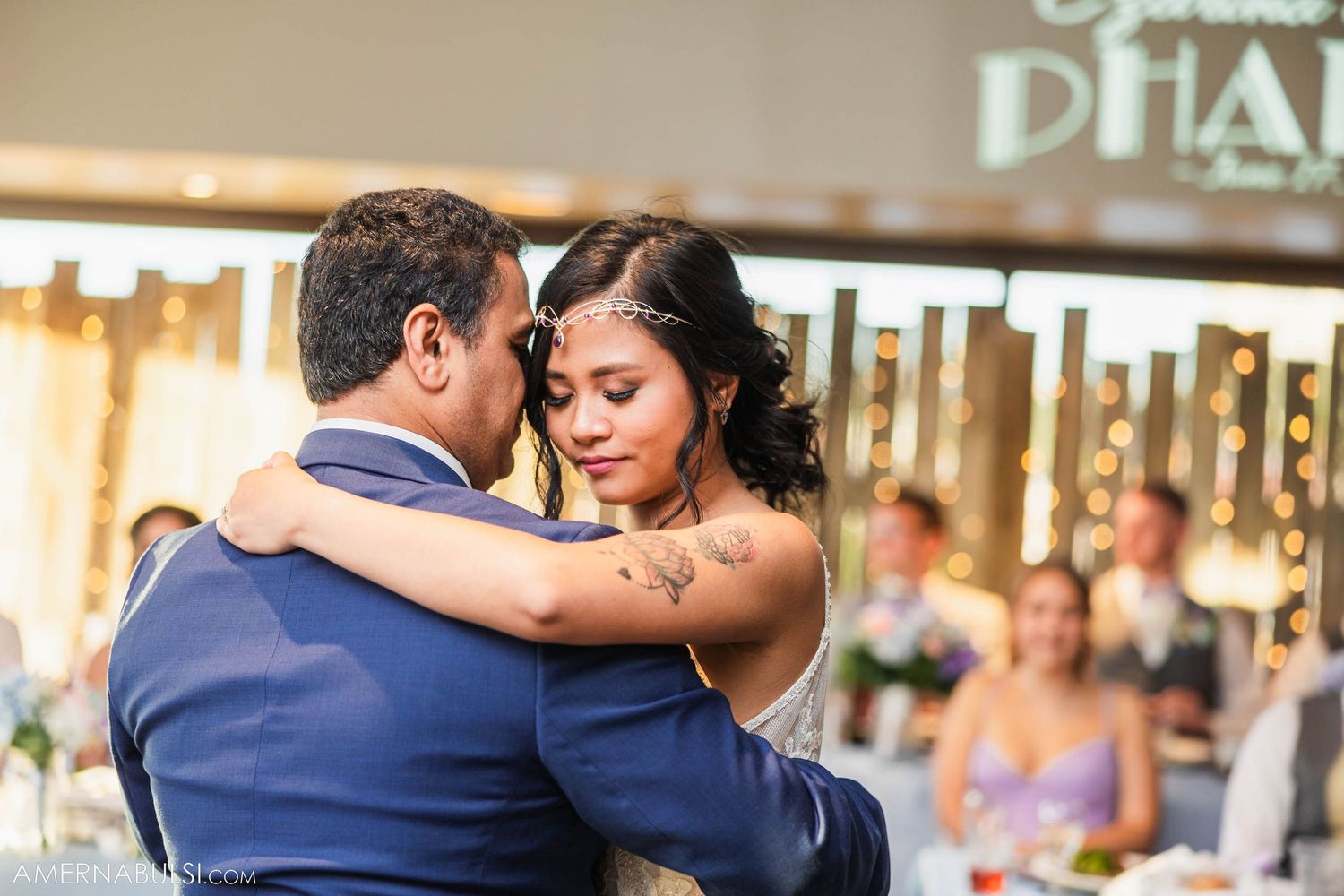 Couple sharing intimate dance moment at wedding reception with rustic decor.