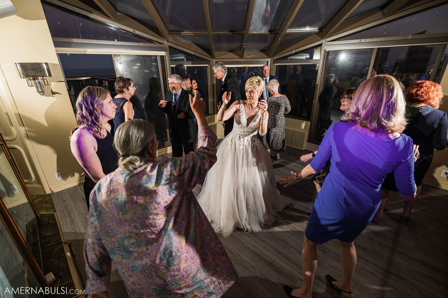 Wedding celebration with guests dancing on indoor dance floor.
