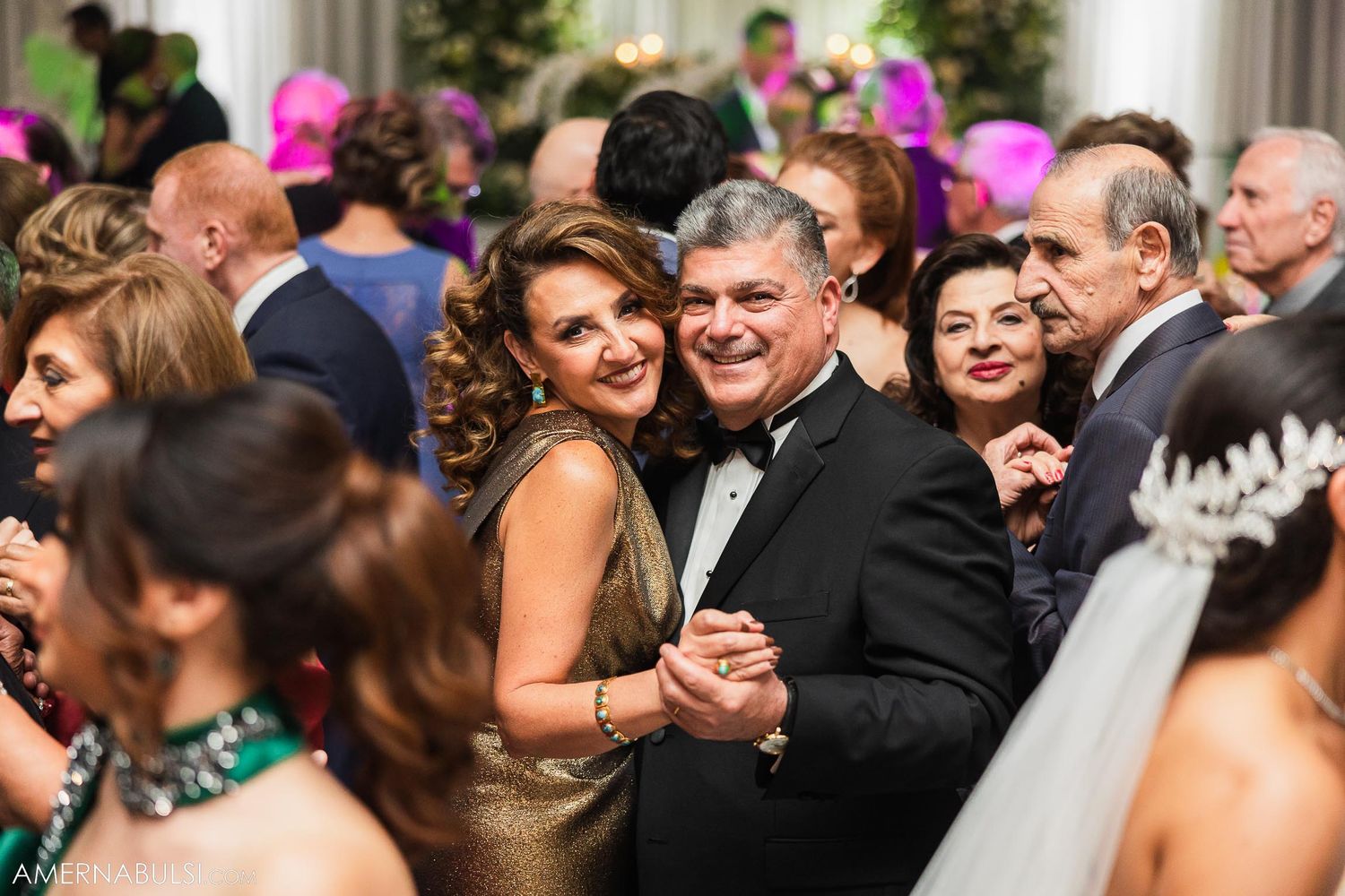 Wedding guests dancing together at an elegant reception with pink decorative accents.