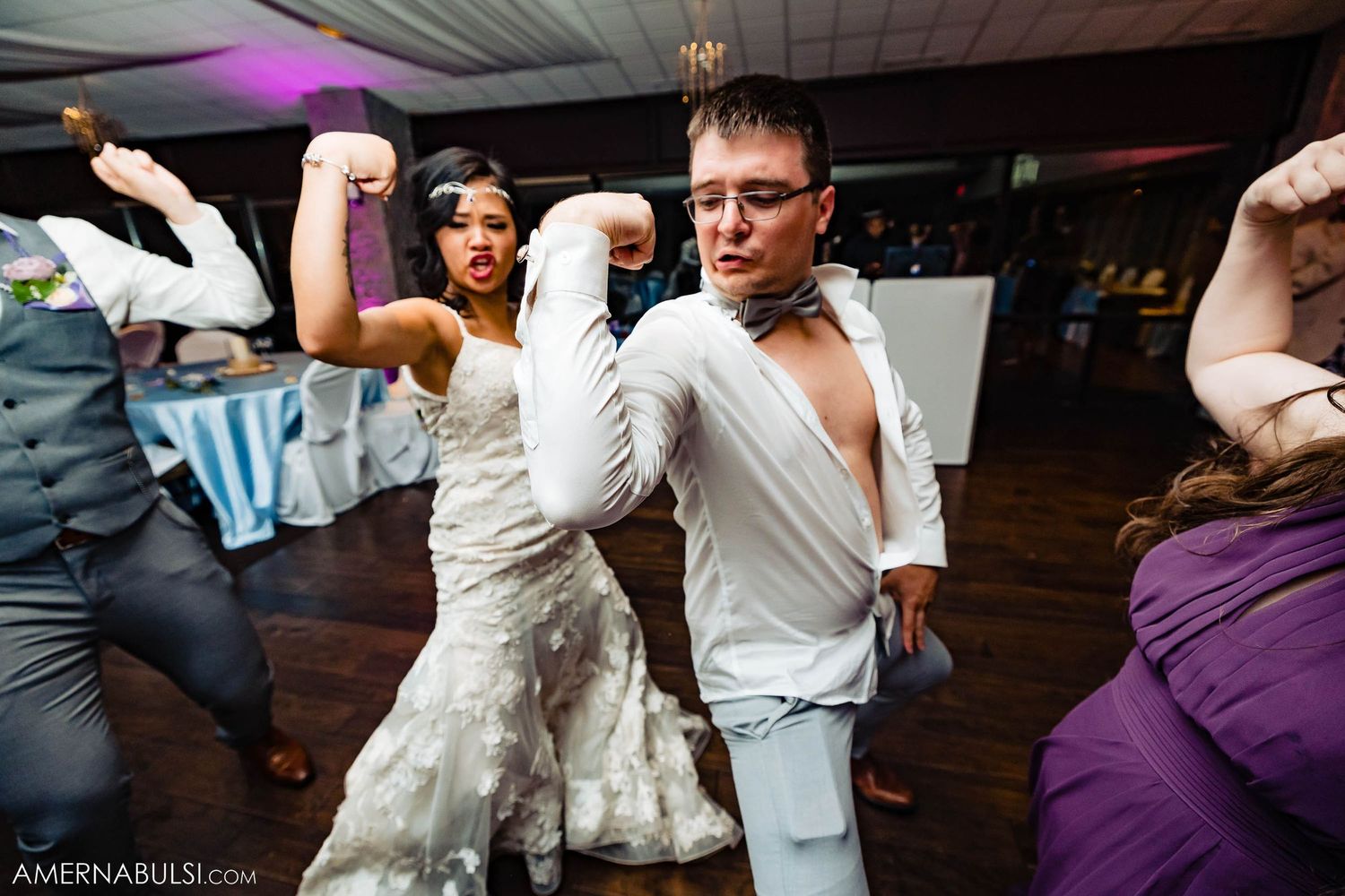 Wedding couple dances wildly on a wooden dance floor during their reception celebration.