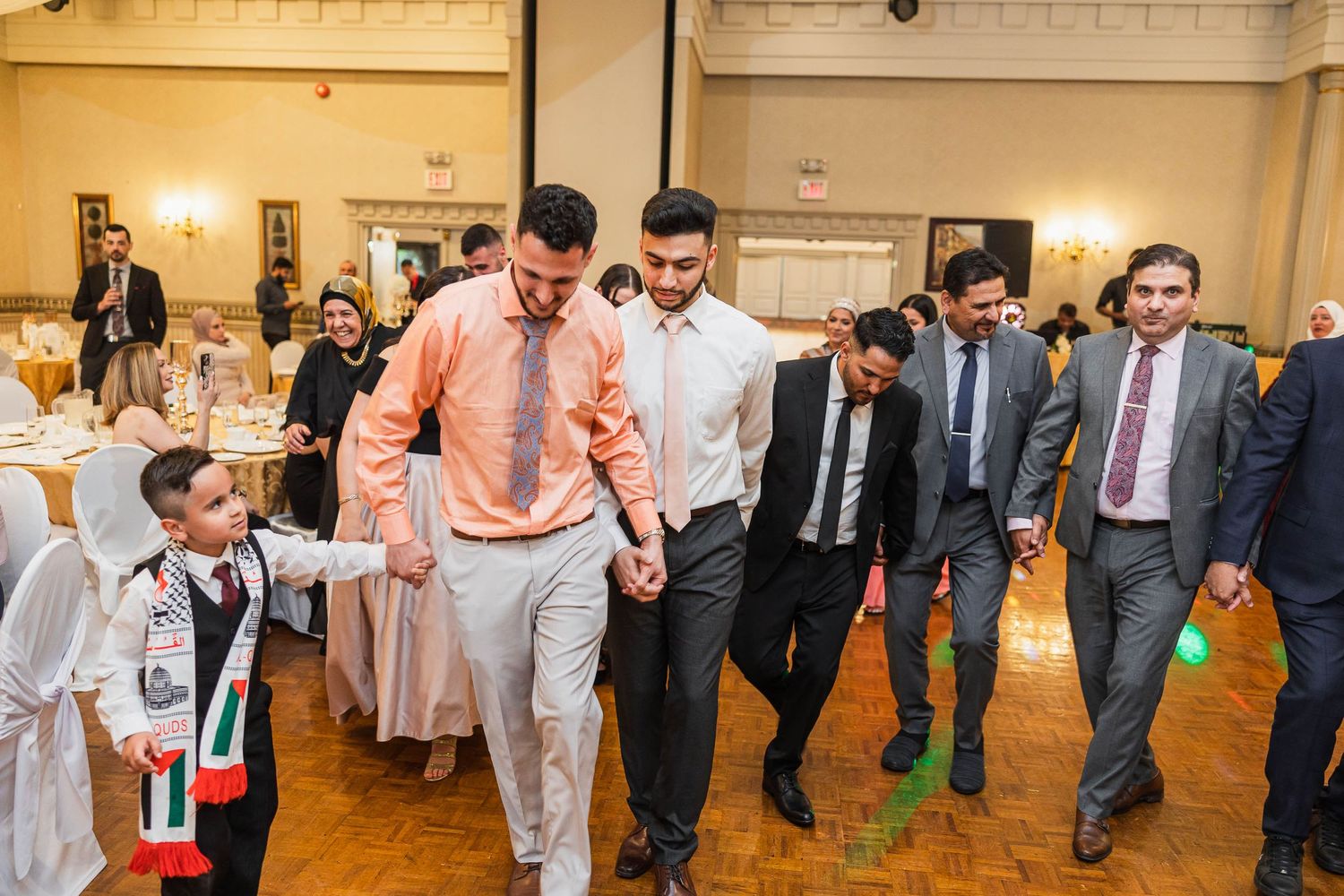 Wedding guests dancing and celebrating together on a ballroom dance floor.