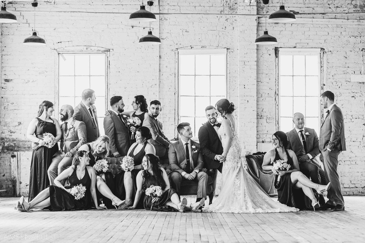 Black and white portrait of wedding party arranged artistically in bright industrial space.