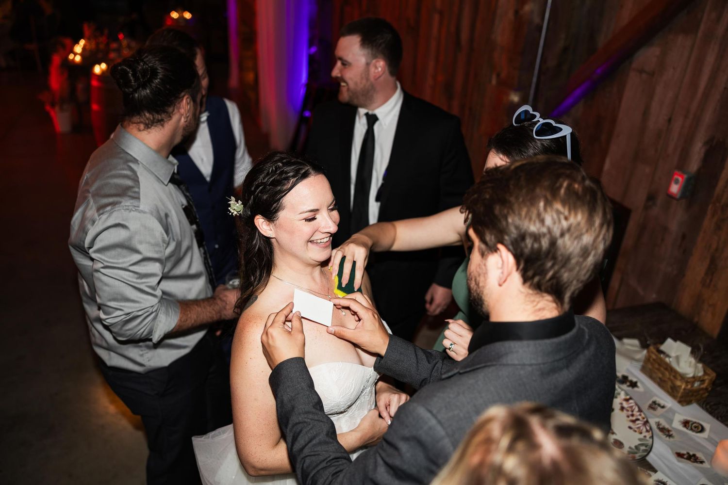 Wedding guests celebrate and dance together during a lively reception in a rustic wooden venue.