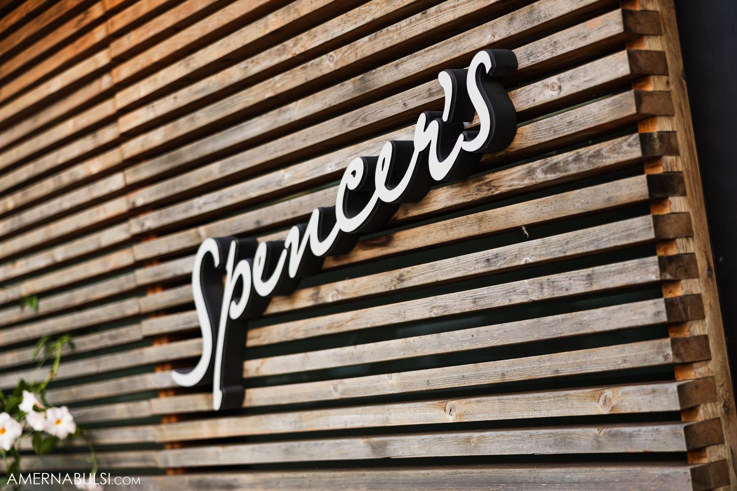 Wooden slatted wall with illuminated 'Spencer's' text sign.
