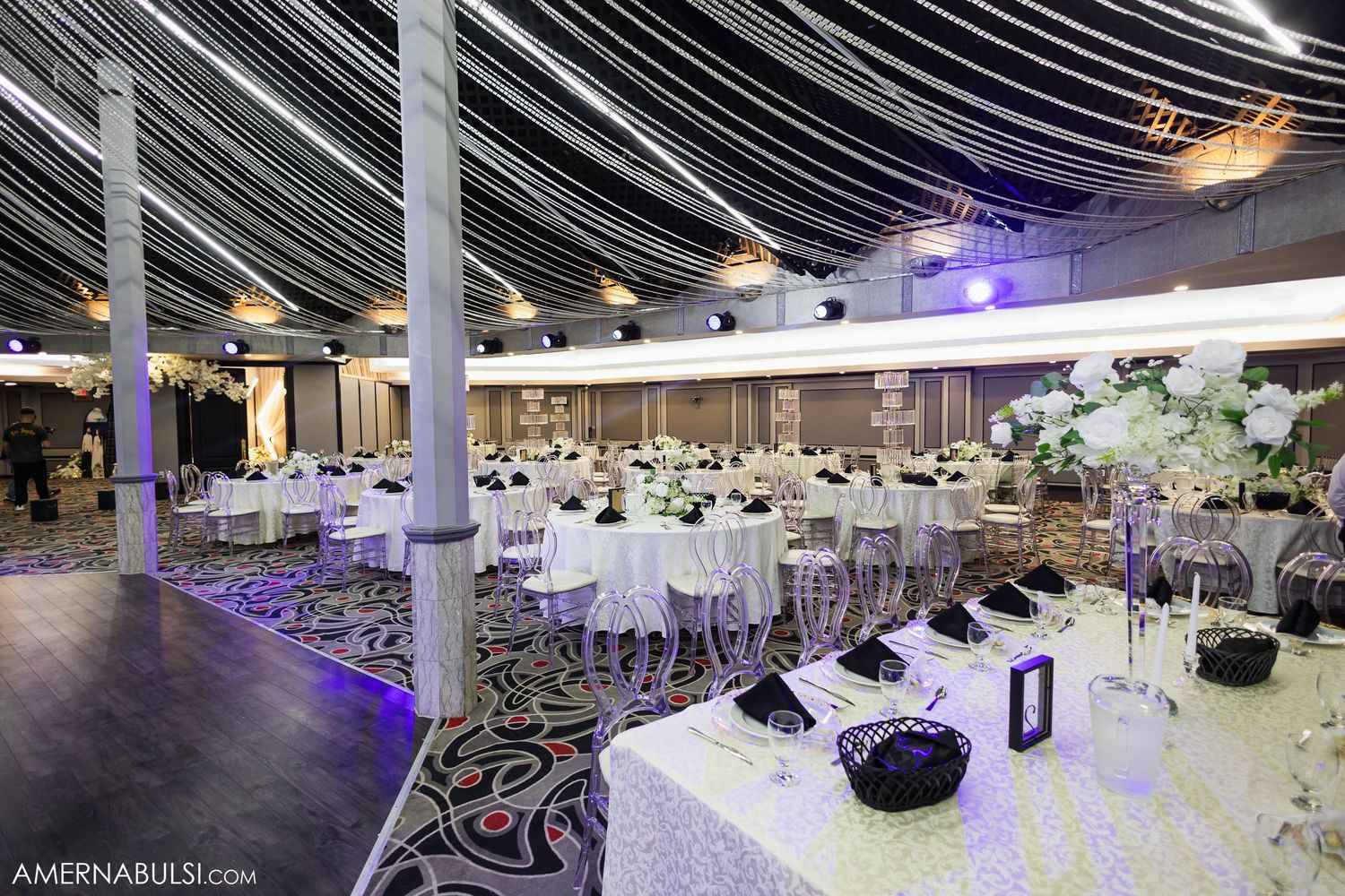 Modern wedding venue space with white columns and purple uplighting creating an atmospheric ambiance.