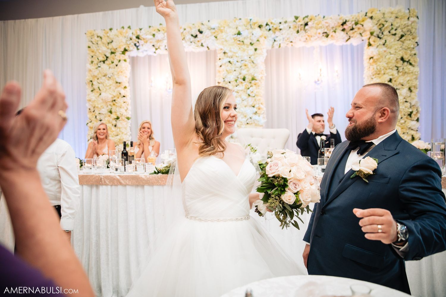 Wedding guests dancing and celebrating on the dance floor at an elegant reception venue.