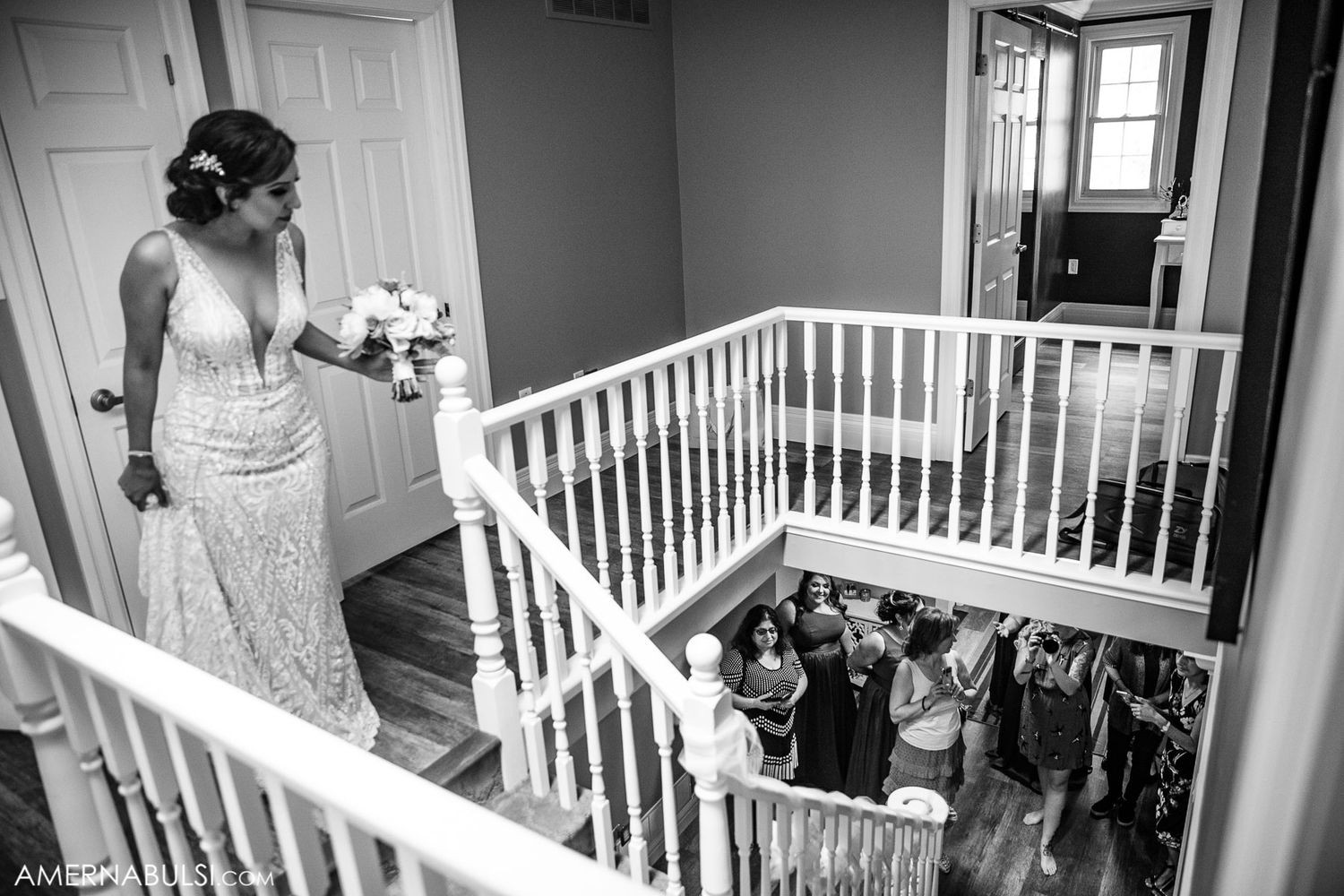 Black and white wedding photograph showing people gathered on a staircase with white railings.