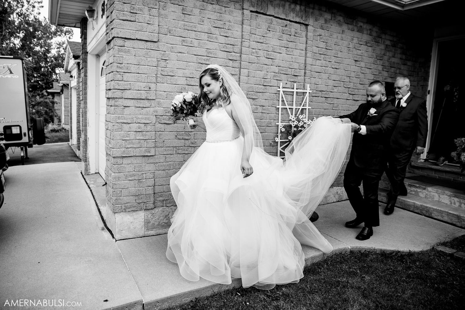 Black and white panoramic view of a couple outside a stone building on their wedding day.