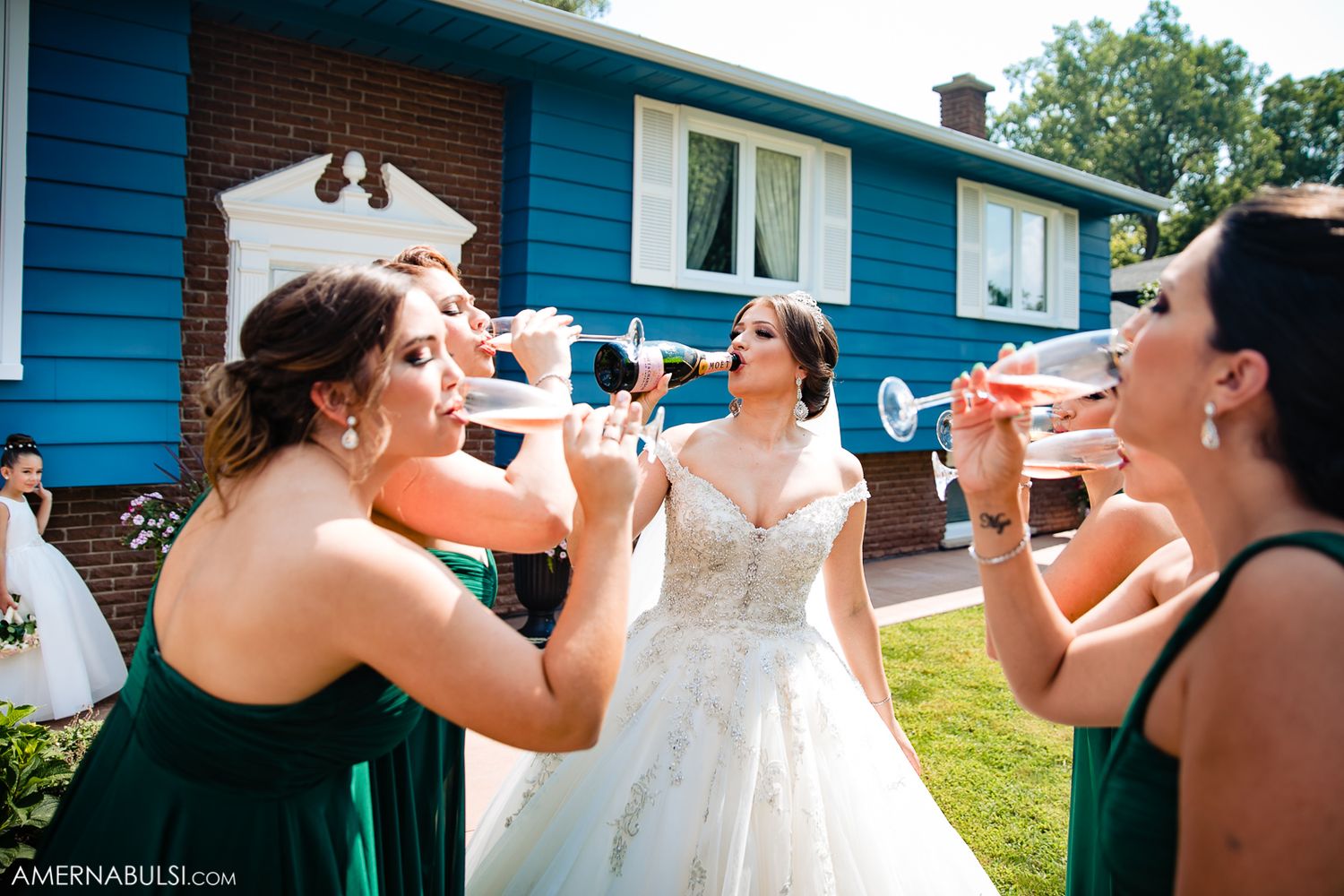 Wedding celebration with group drinking champagne outside bright blue house.