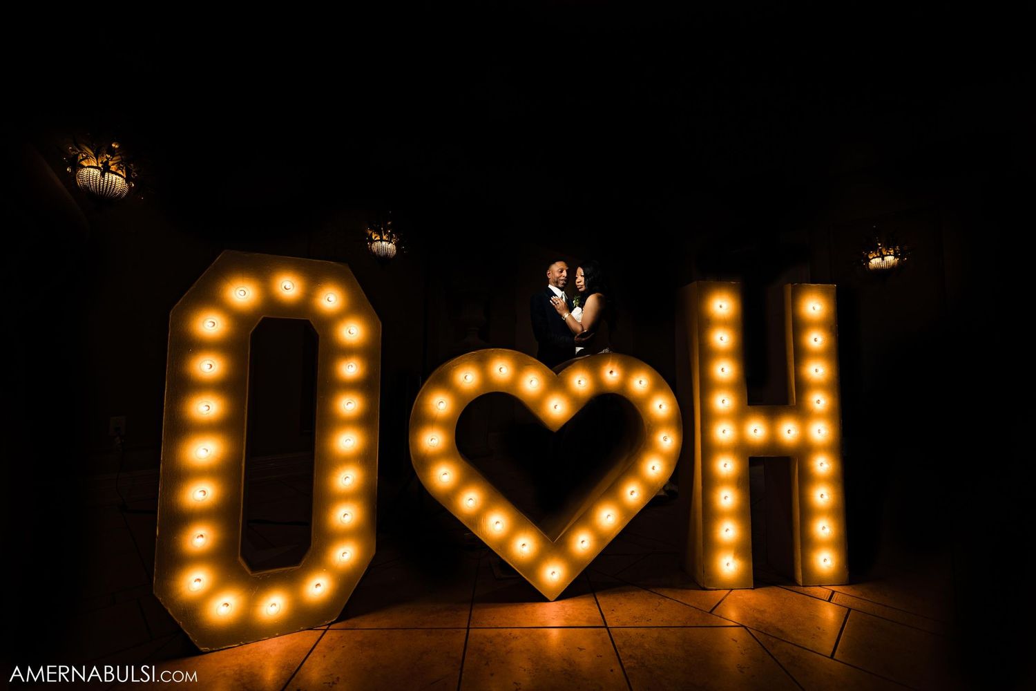 Illuminated marquee letters spelling 'OH' with heart symbol against dark background.