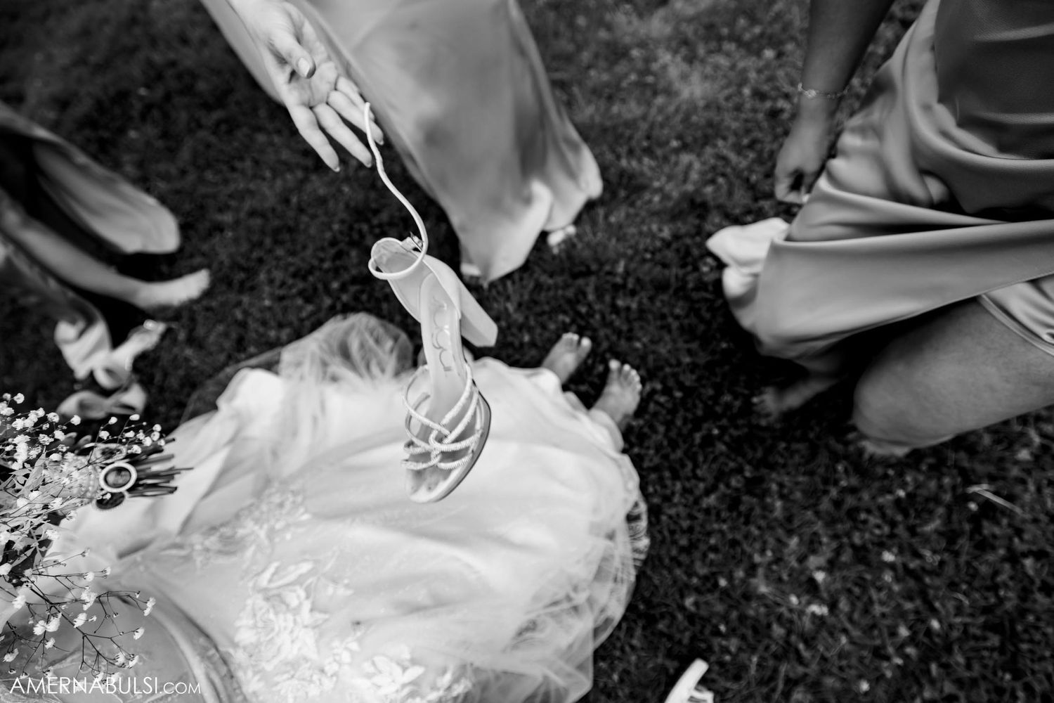Black and white detail shot of hands arranging wedding dress.