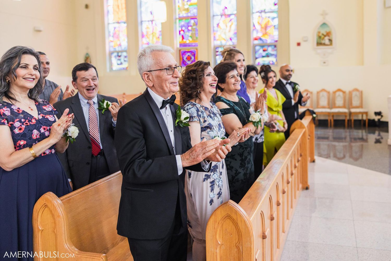 Wedding guests standing in church pews during the ceremony celebration.