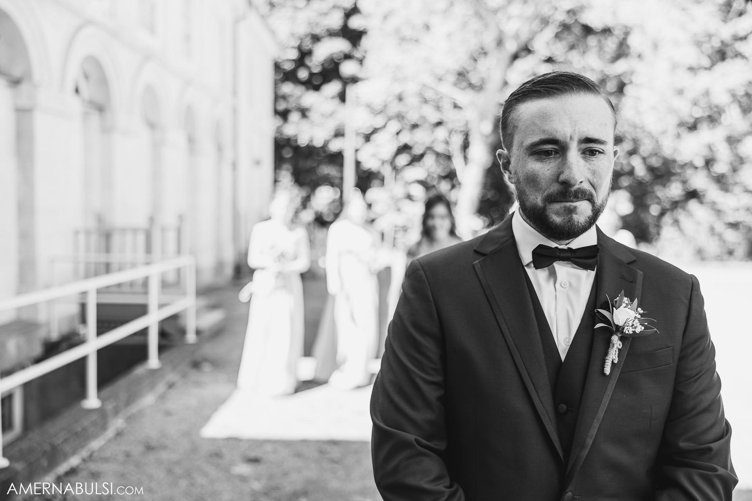 Black and white portrait of groom in tuxedo with boutonniere outdoors.