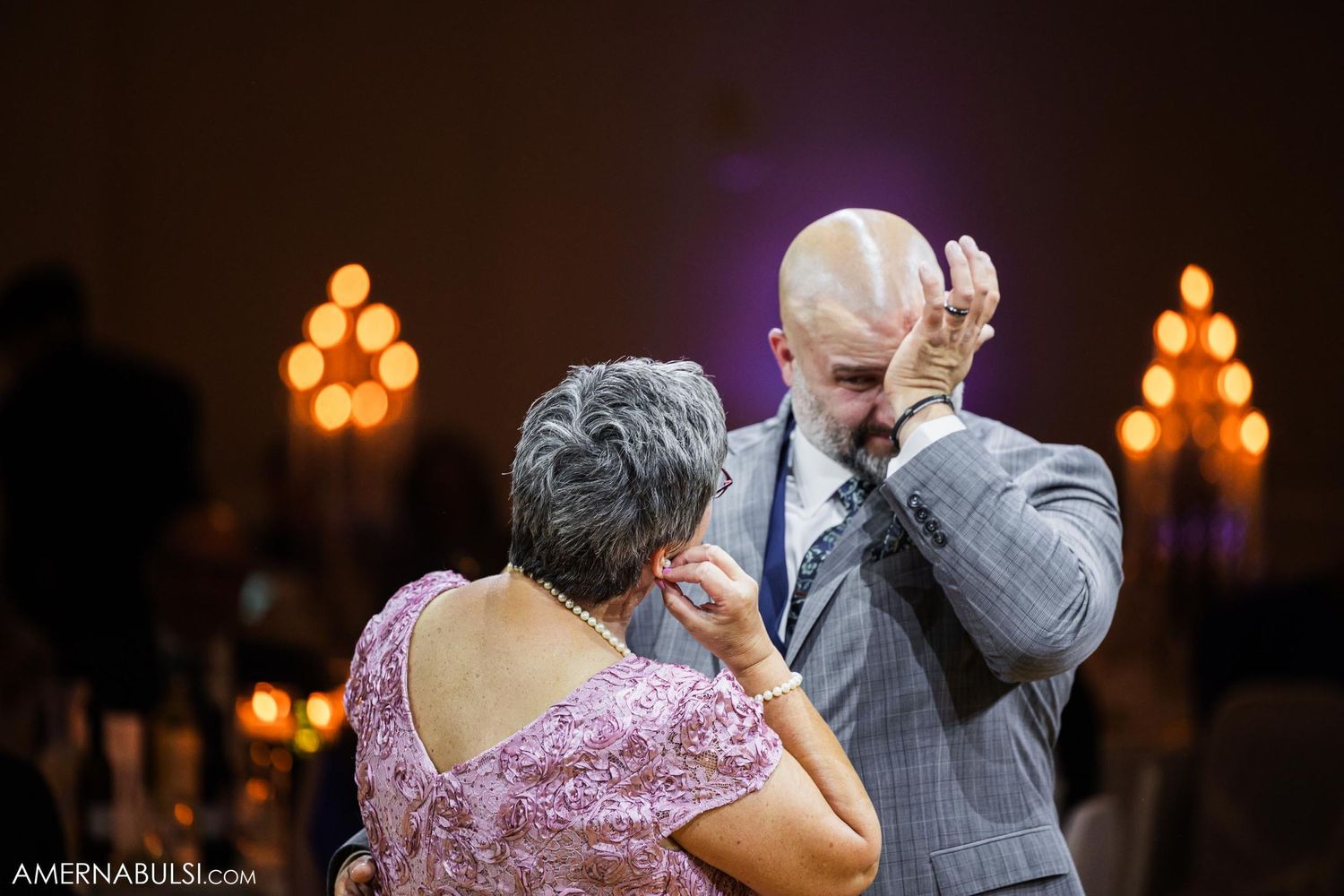 Emotional dance moment during reception with warm lighting and candlelit ambiance.