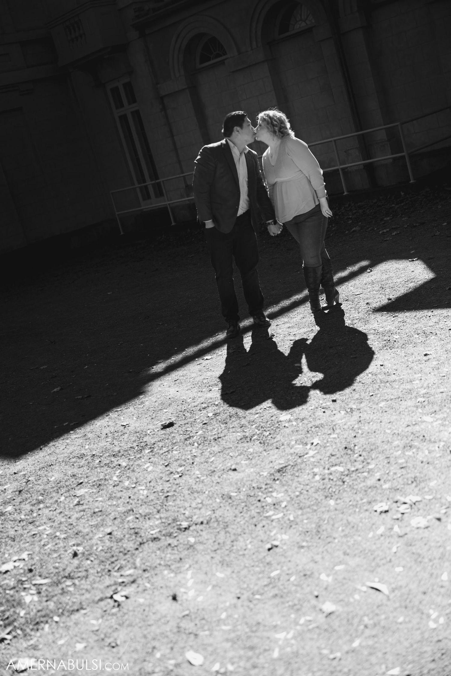 A black and white silhouette photo of a couple with dramatic shadows on the ground.