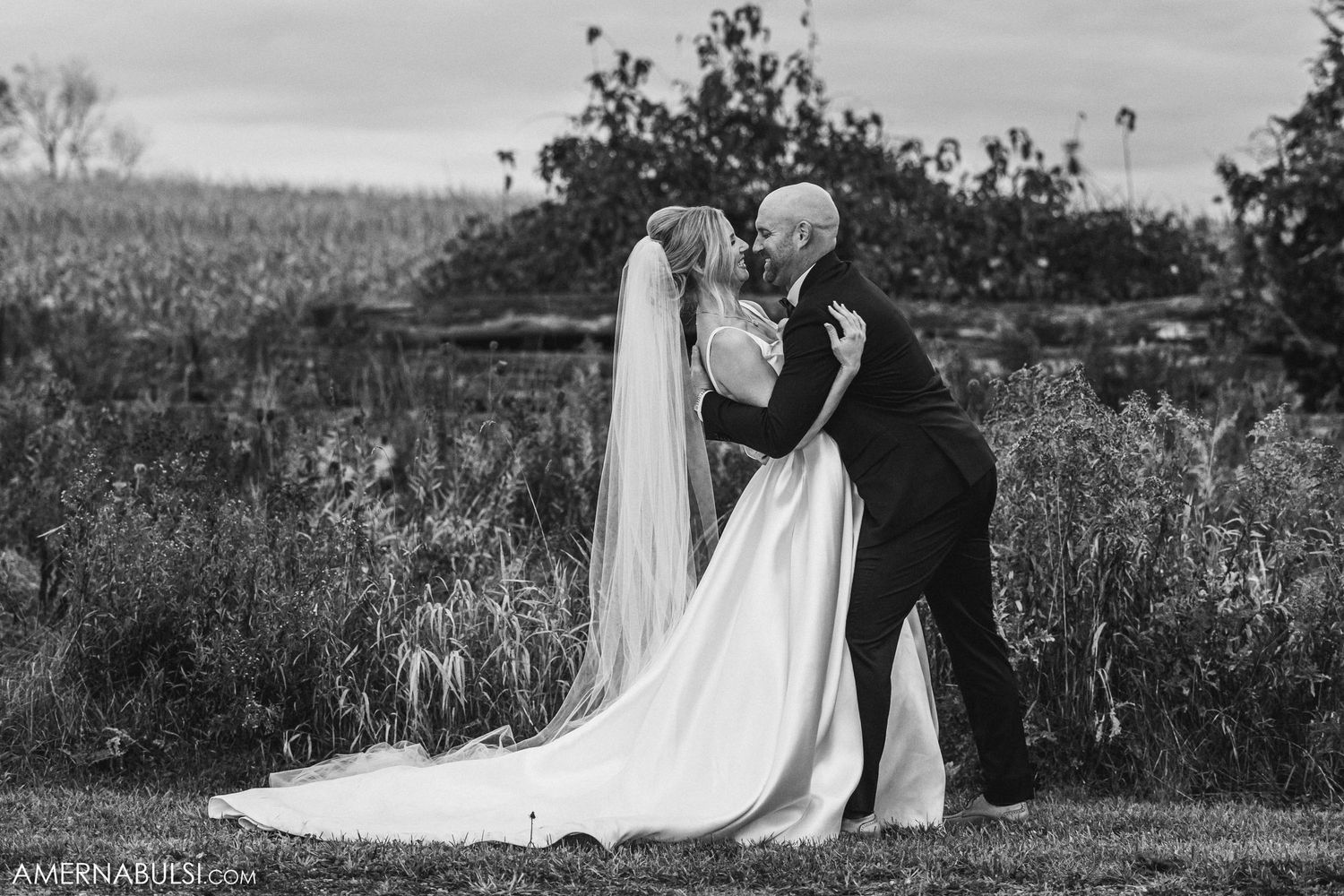 Elegant black and white wedding photo showing newlyweds embracing outdoors.