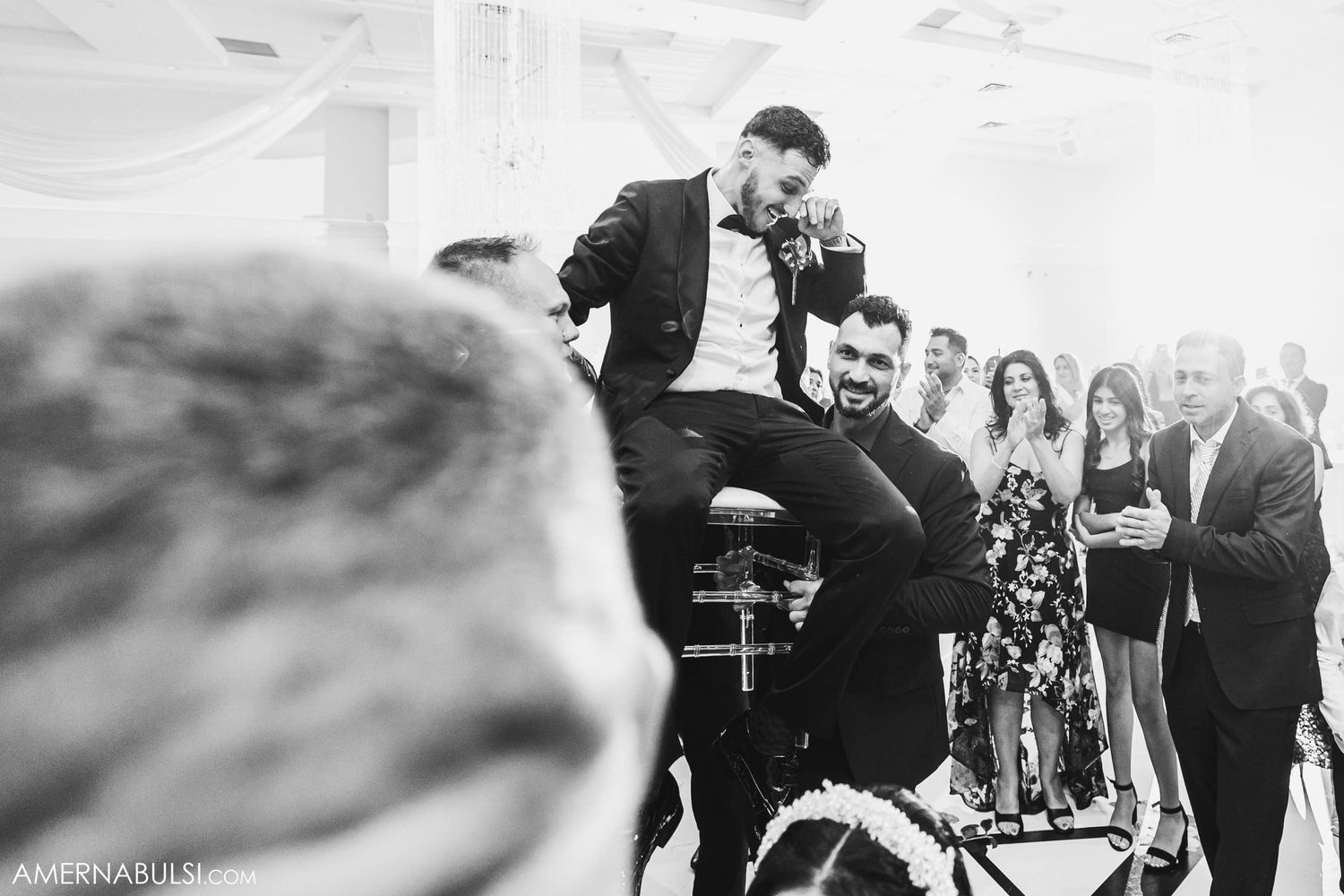 Black and white photo of wedding celebration with guest being lifted in celebration.