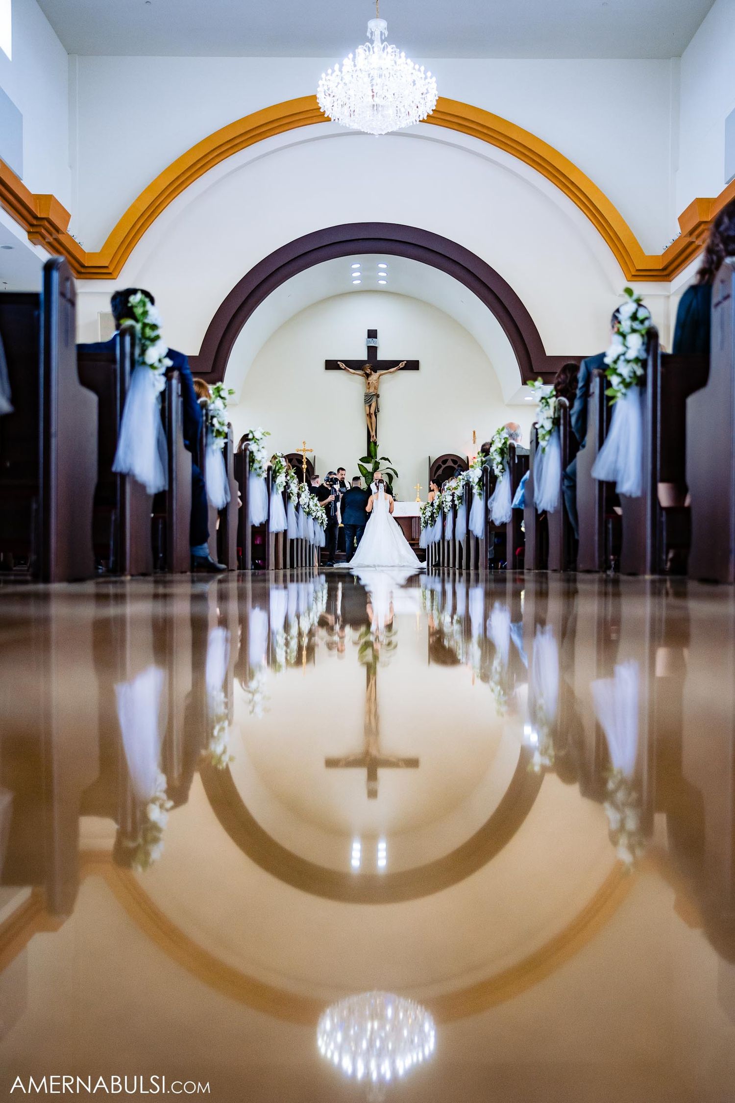 Dramatic church aisle shot with arches and crucifix reflected in polished floor.