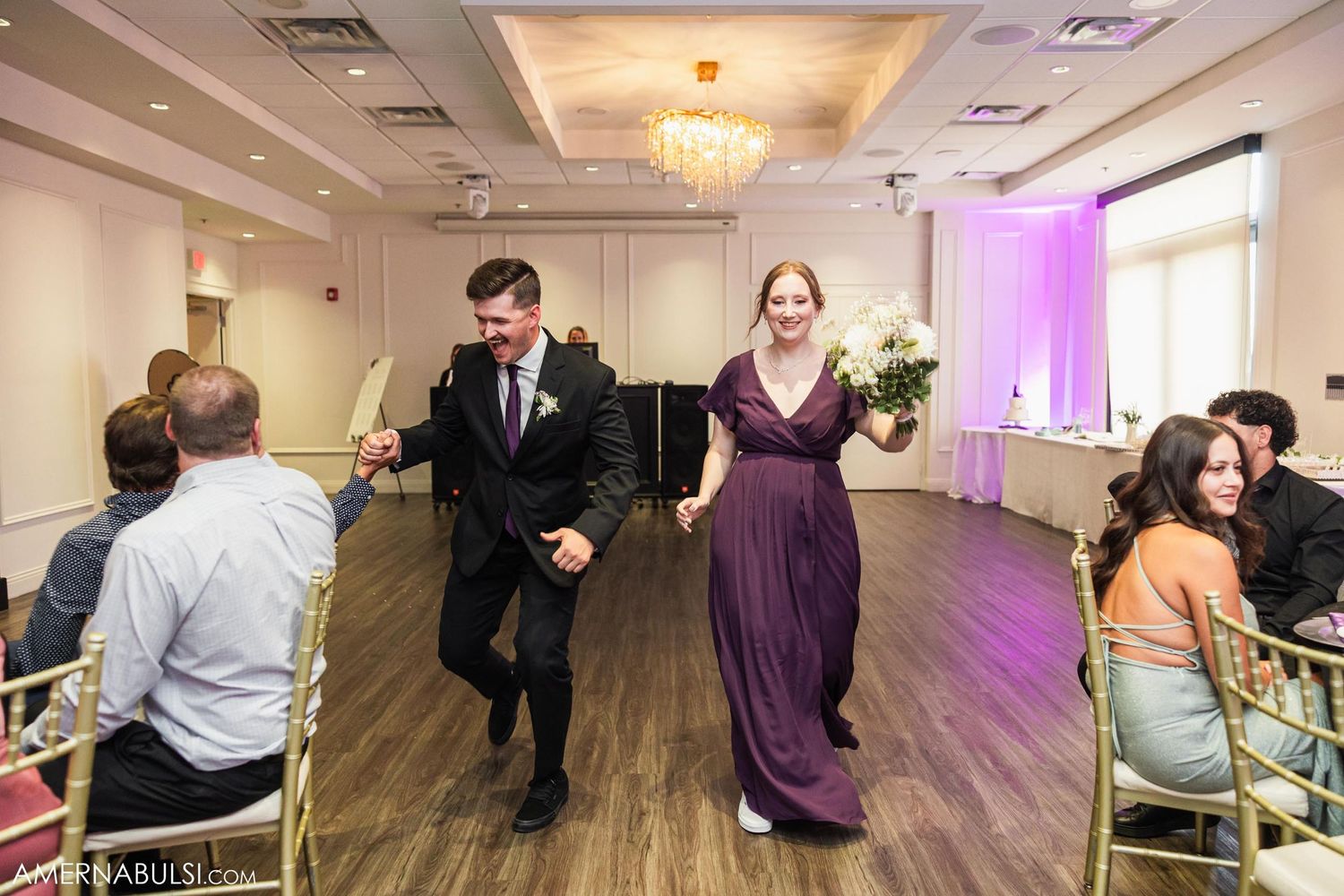 Wedding party members dance enthusiastically through the reception hall.