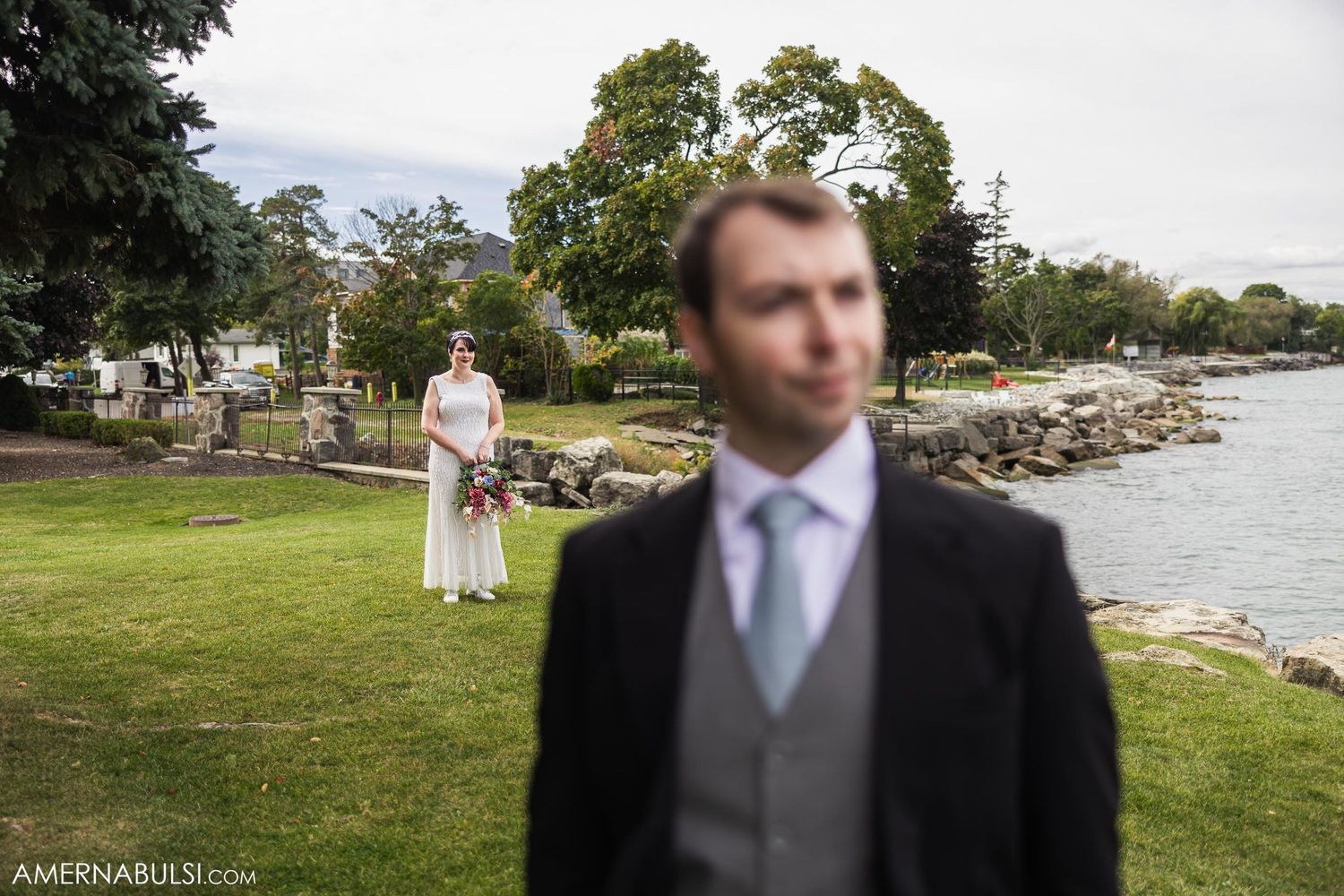 Creative wedding portrait with figure in foreground and background composition by waterfront.