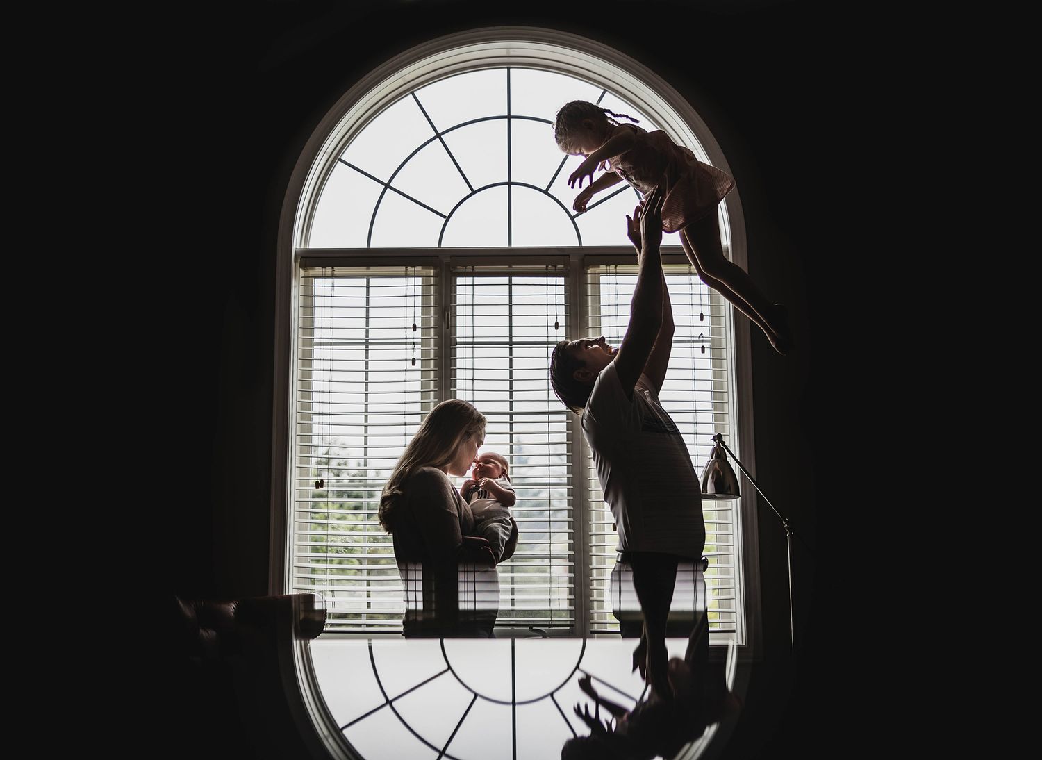 Dramatic silhouettes of dancers performing against a large arched window.