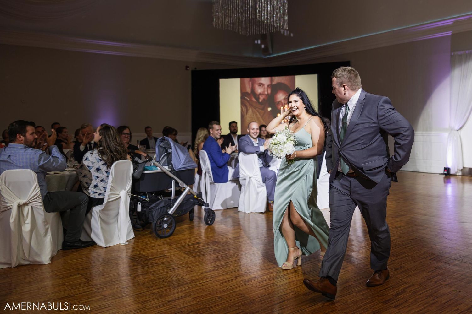 Celebration on the dance floor at wedding reception with guests watching from decorated tables.