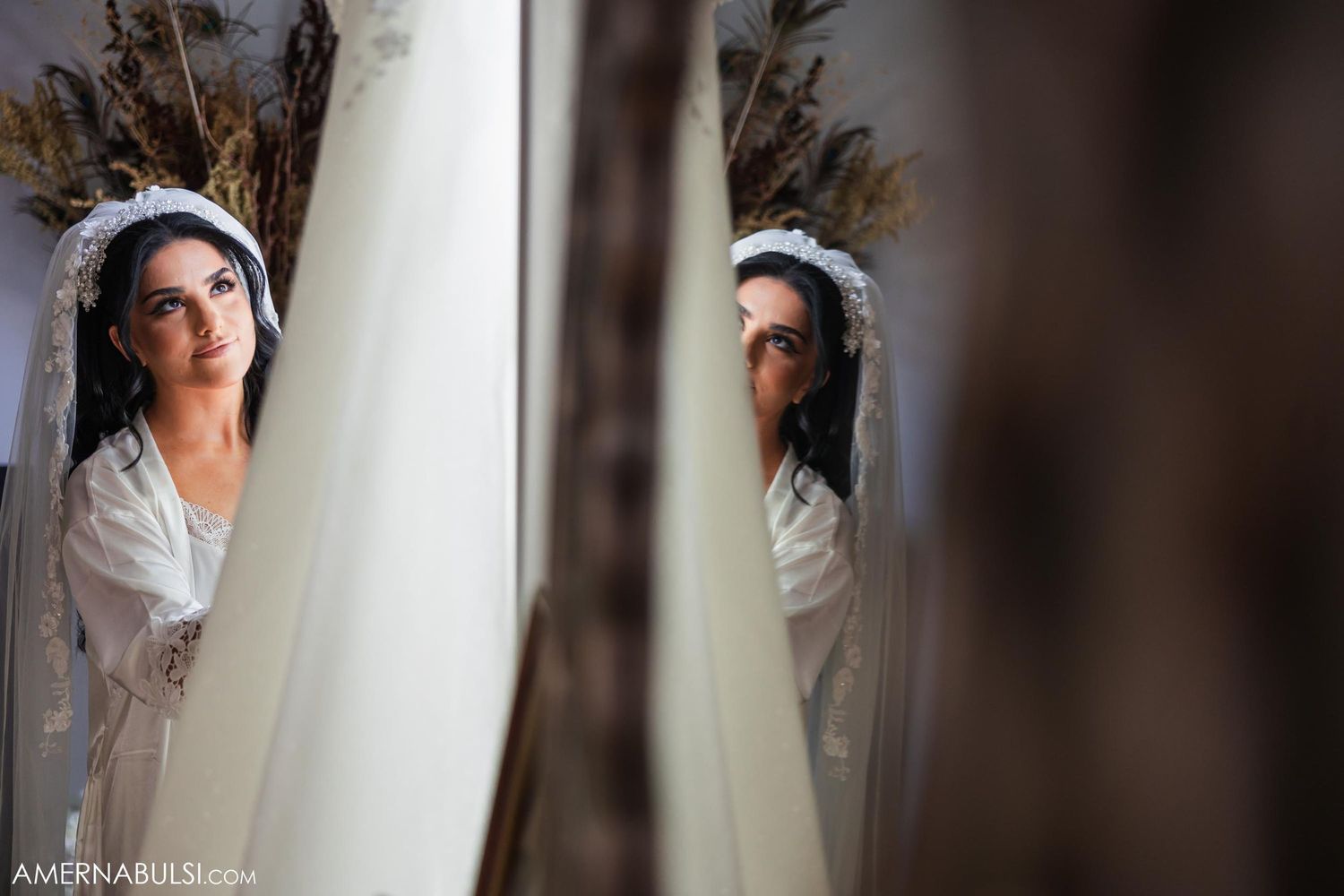 Artistic mirrored reflection shot through decorative elements with dried flowers in frame.