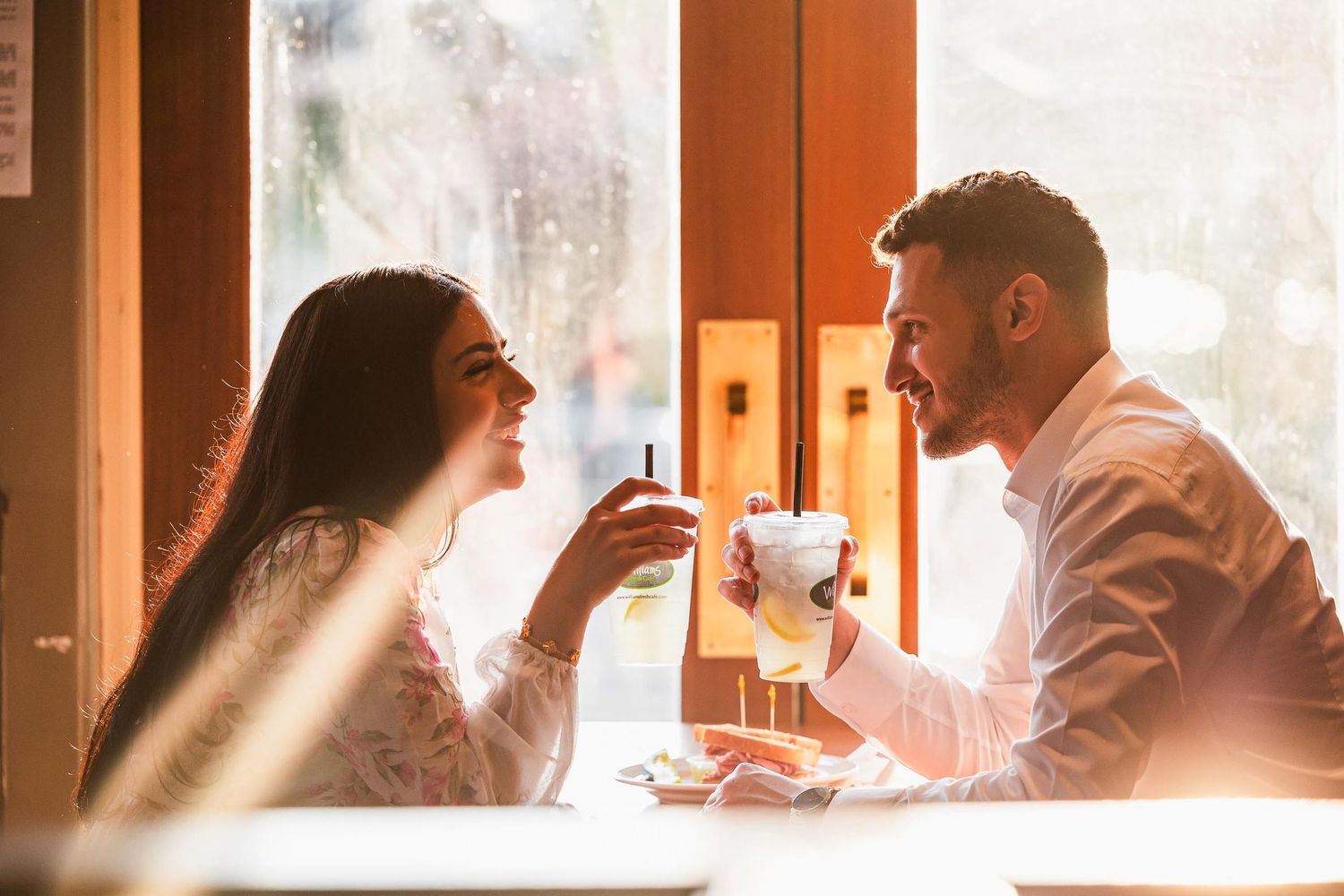 Sunlit coffee shop scene through window with warm golden light.