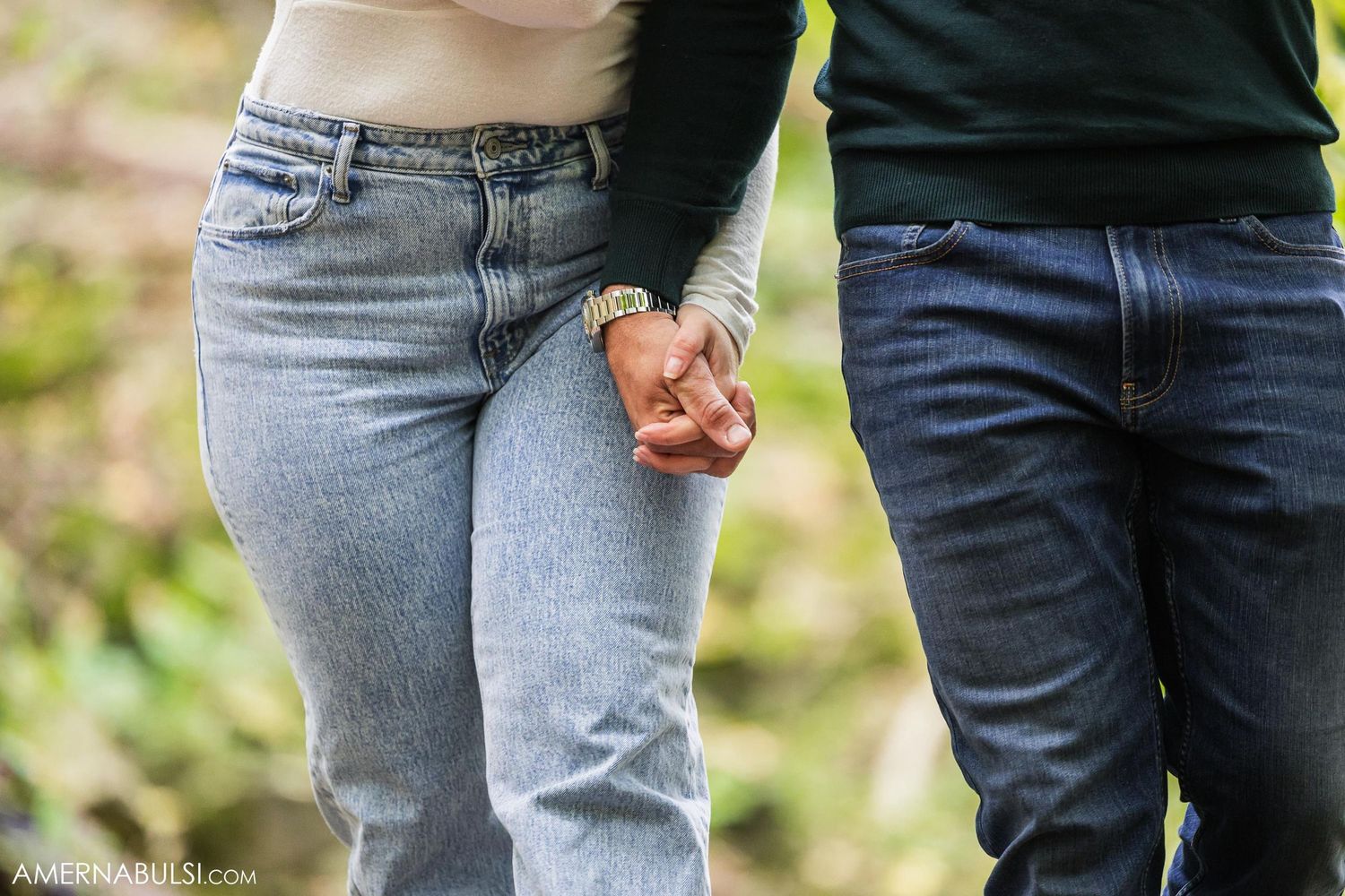 A close-up shot of two people holding hands while wearing denim jeans.