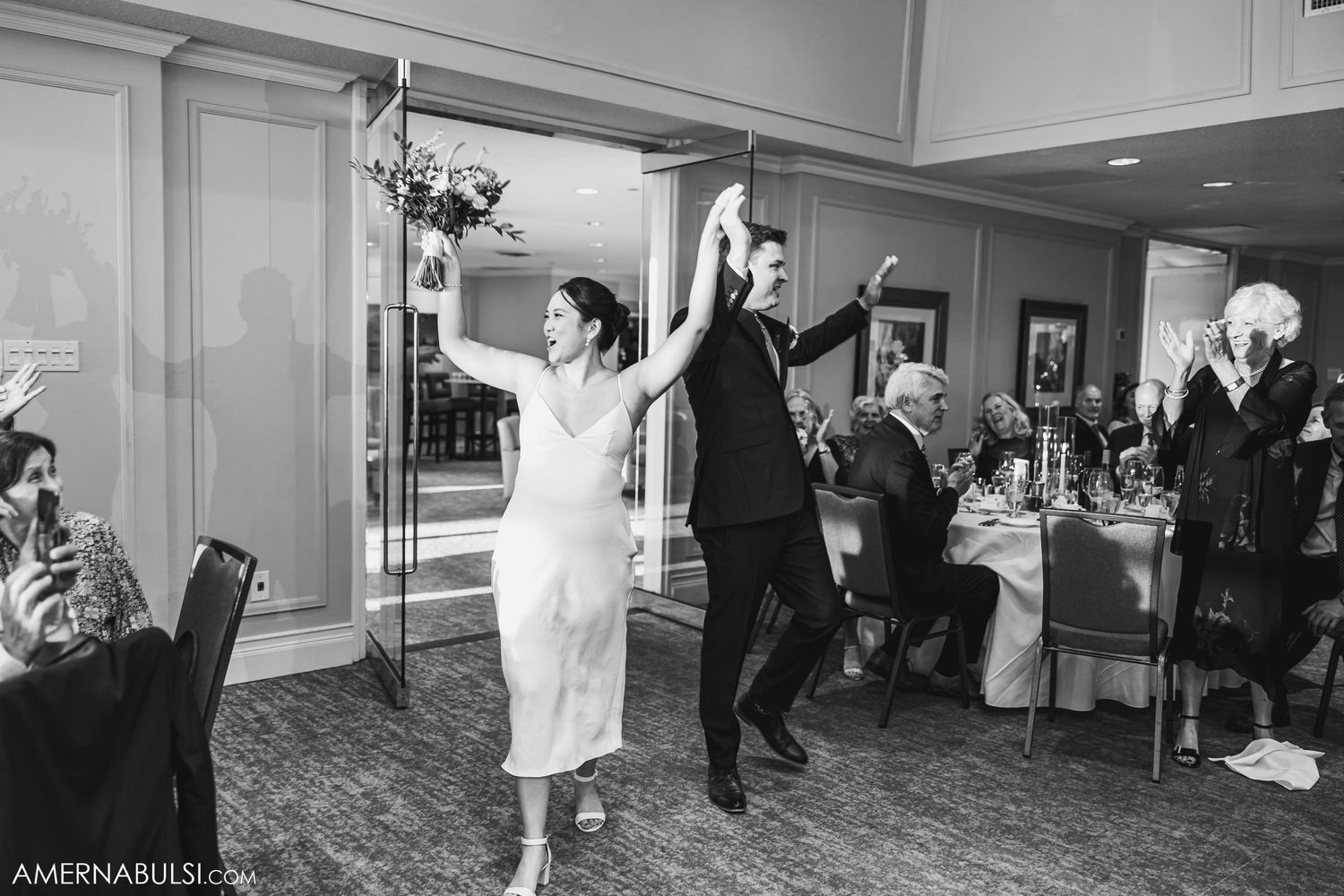 Wedding guests dance with raised arms in a black and white photo of the reception.