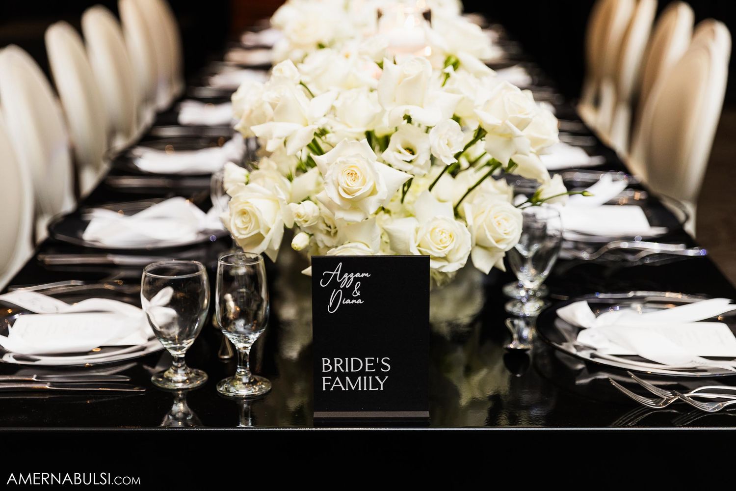 Formal table setting with white roses centerpiece and bride's family place card.