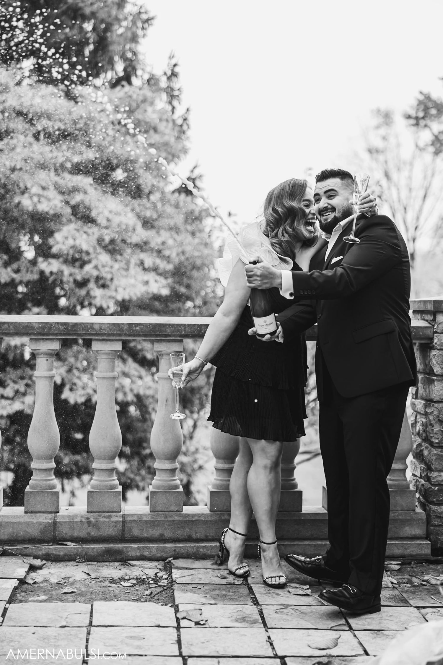 A couple dancing and celebrating with champagne on a stone patio.