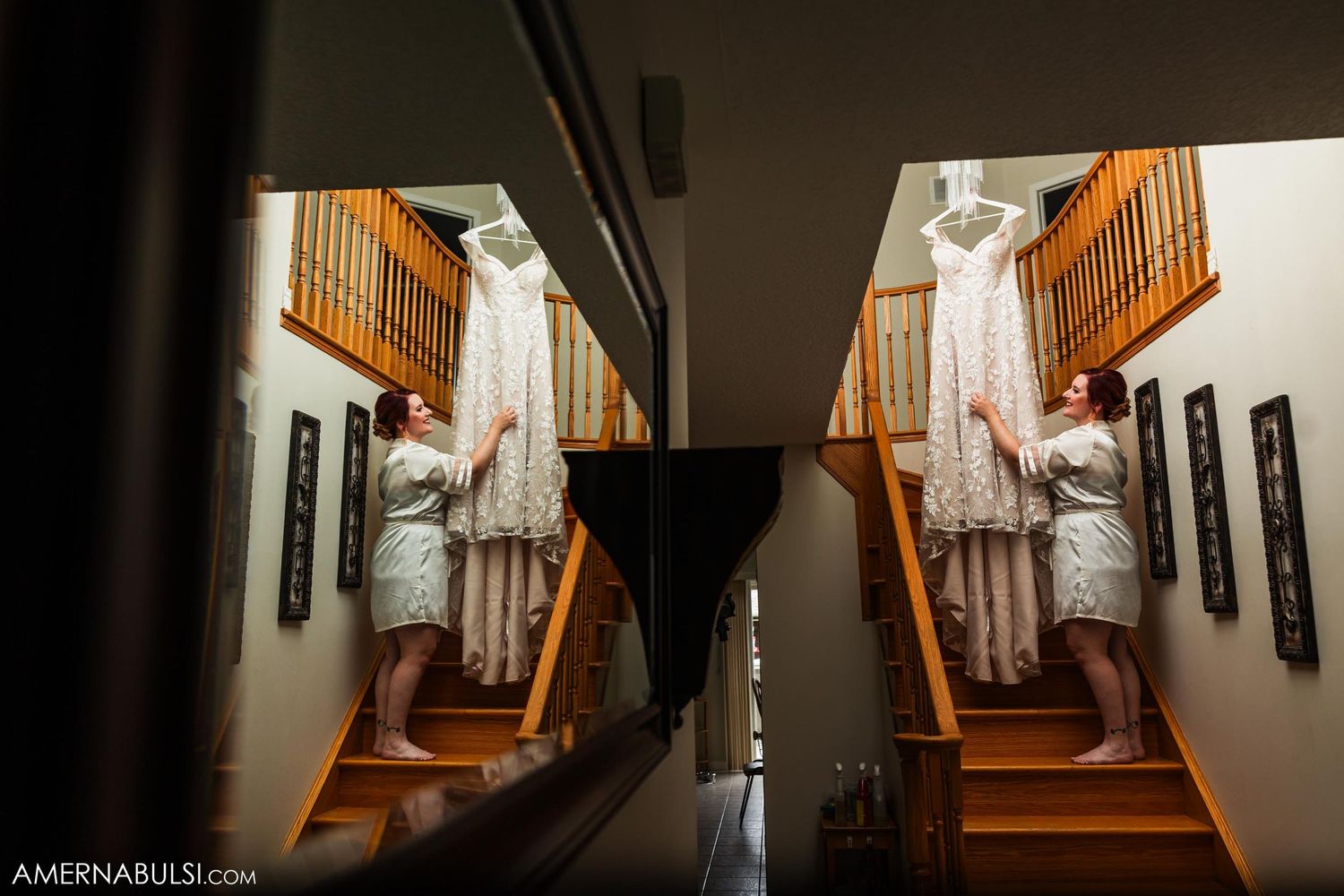 Wedding dress hanging in stairwell with wooden banister and wall art visible.