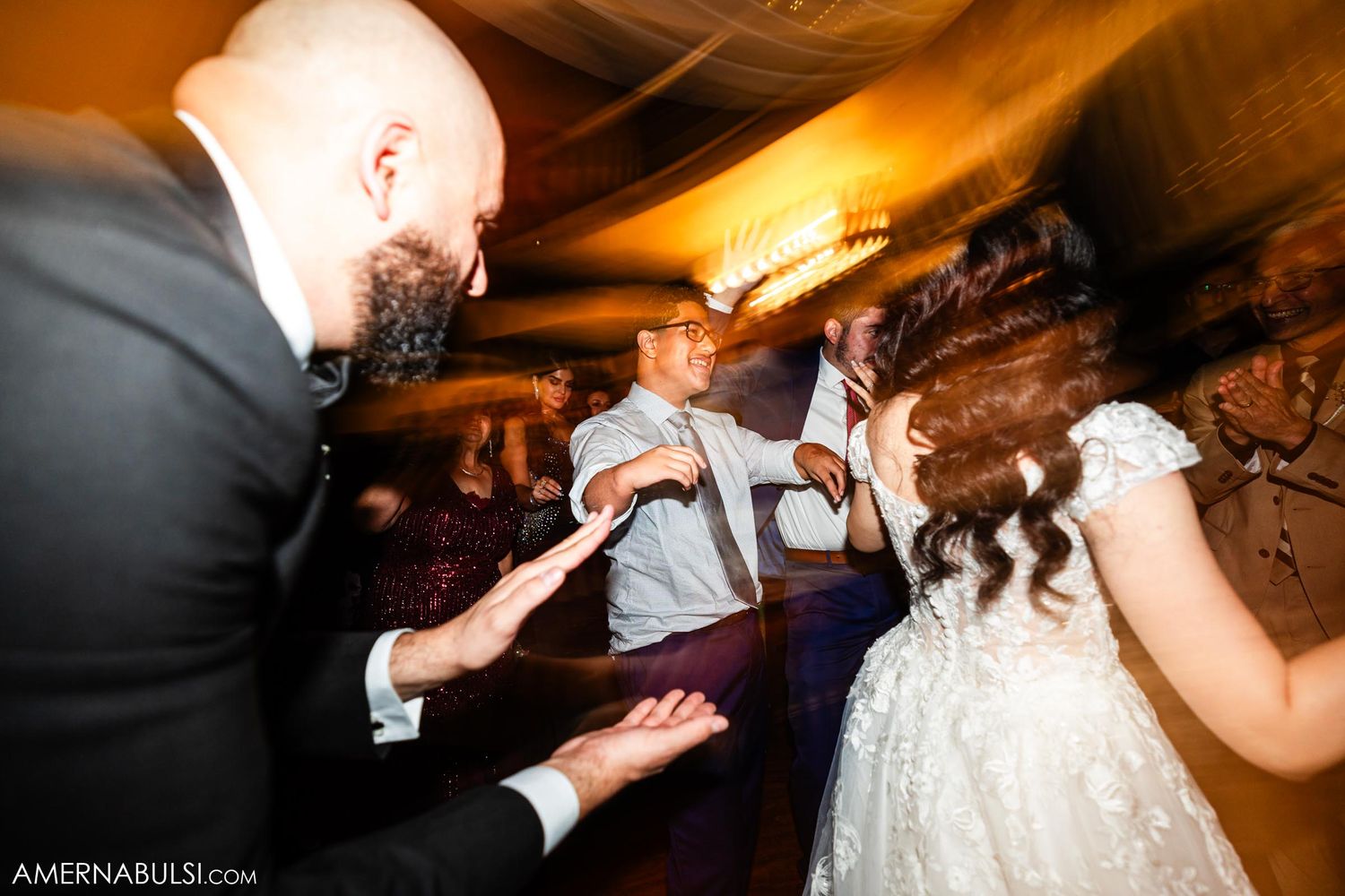 Wedding guests dance energetically on the reception dance floor with motion blur effects.
