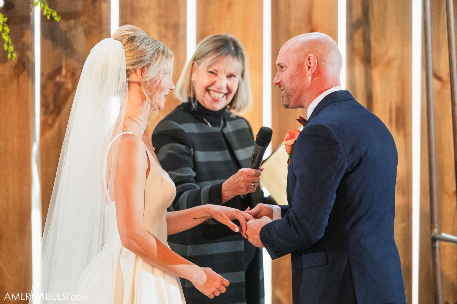 Joyful wedding ceremony moment with officiant in striped coat conducting service.