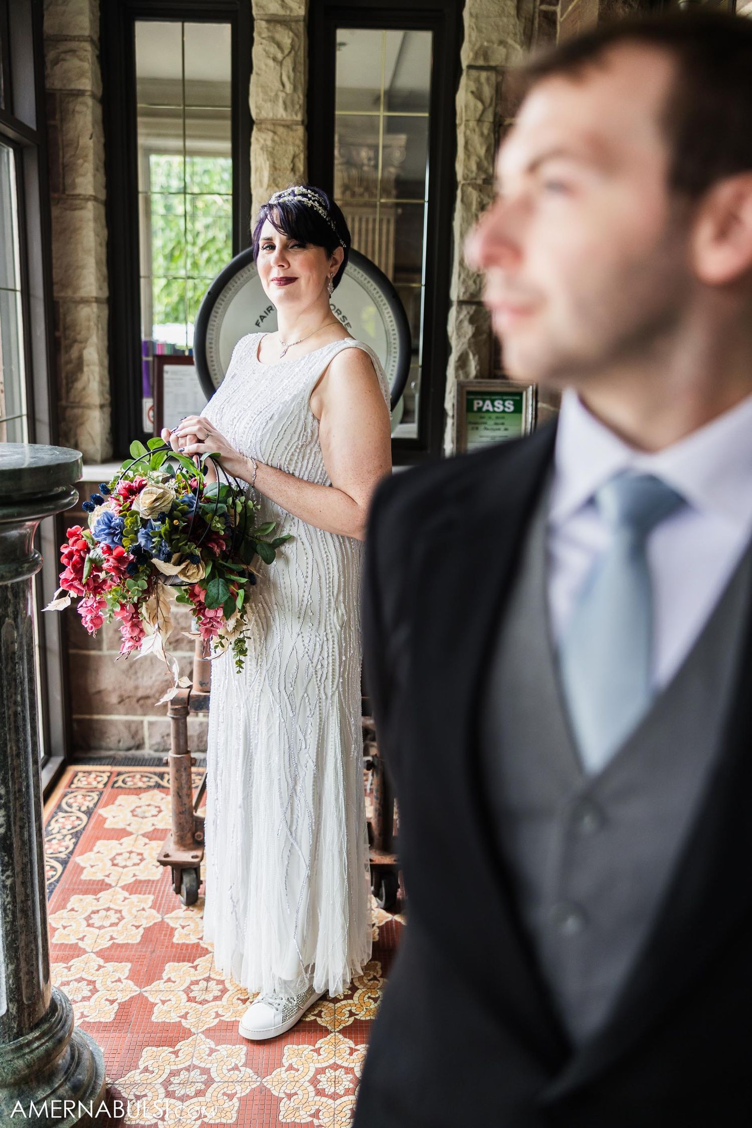 Wedding portrait in a rustic interior featuring elegant attire and vibrant floral bouquet.