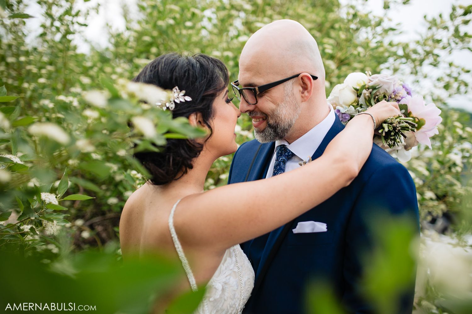 Romantic outdoor wedding ceremony moment captured through green foliage.