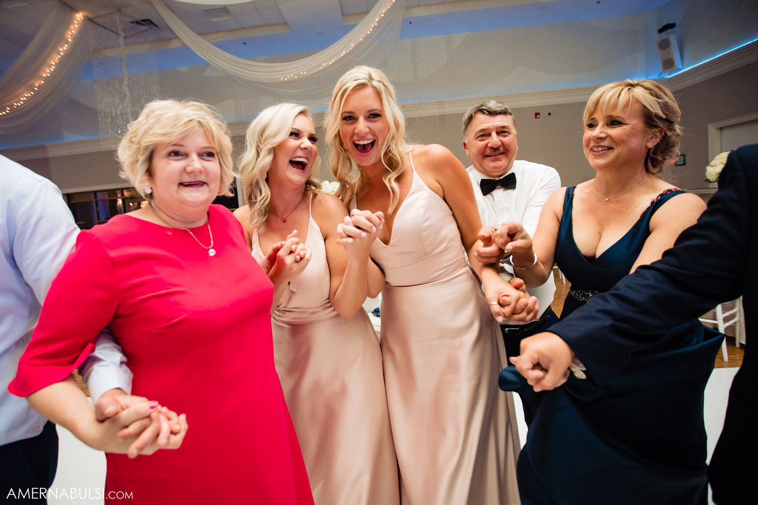 A group of wedding guests dancing and celebrating together on the dance floor at a reception.