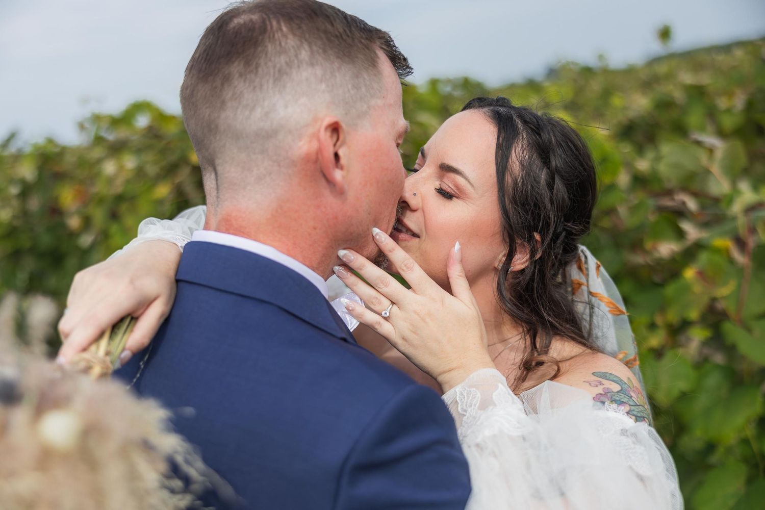 A romantic embrace between newlyweds in a vineyard setting.