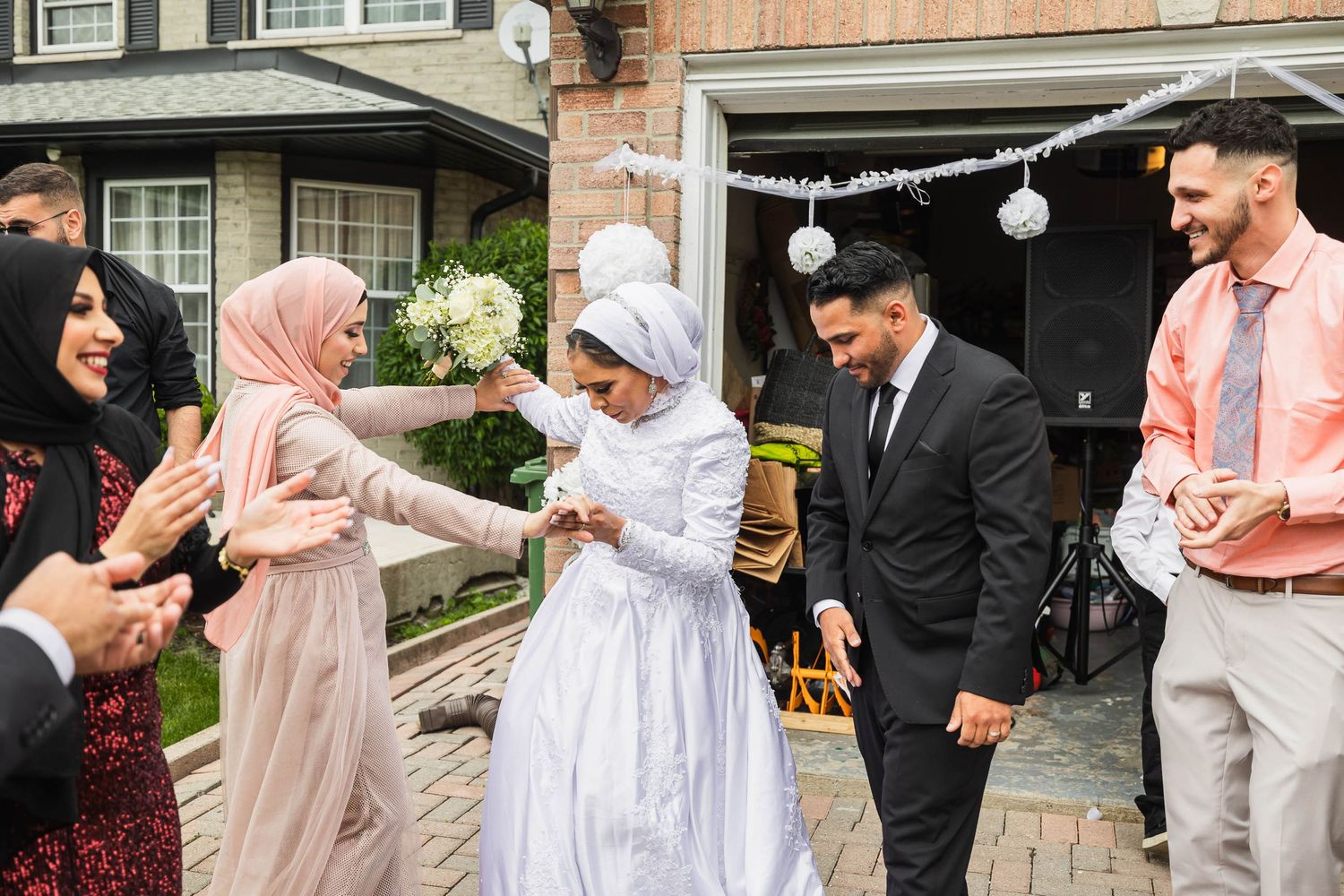 Wedding guests interact and celebrate during an outdoor reception at a brick venue.