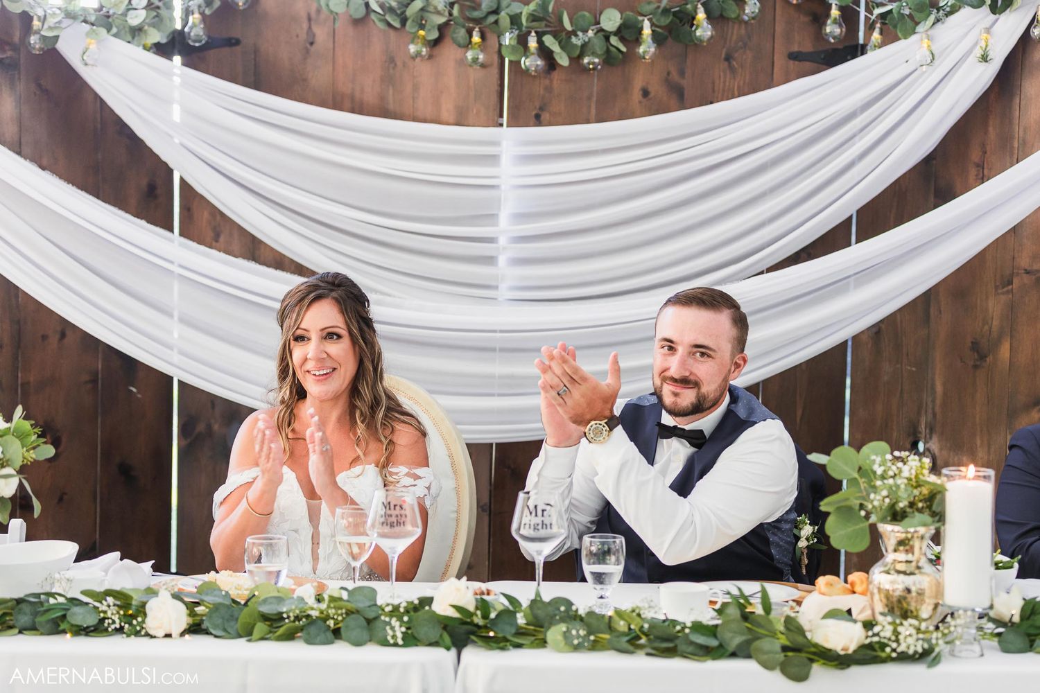 Wedding speech being delivered at reception while couple listens from decorated head table.