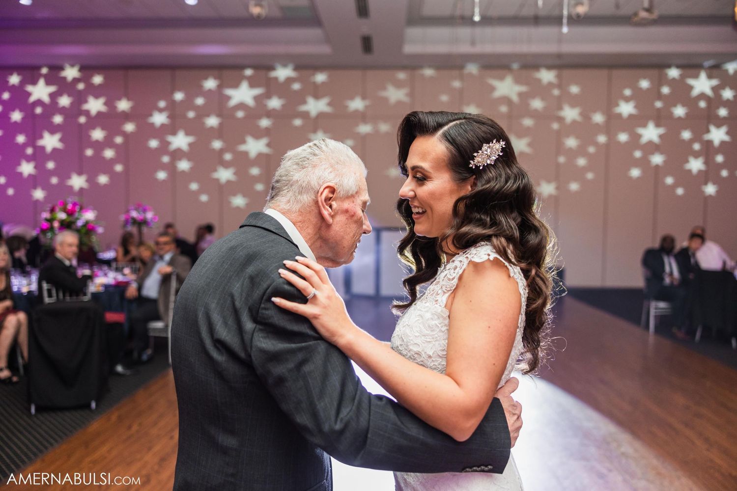 A touching moment during a wedding reception dance on a decorated ballroom floor.