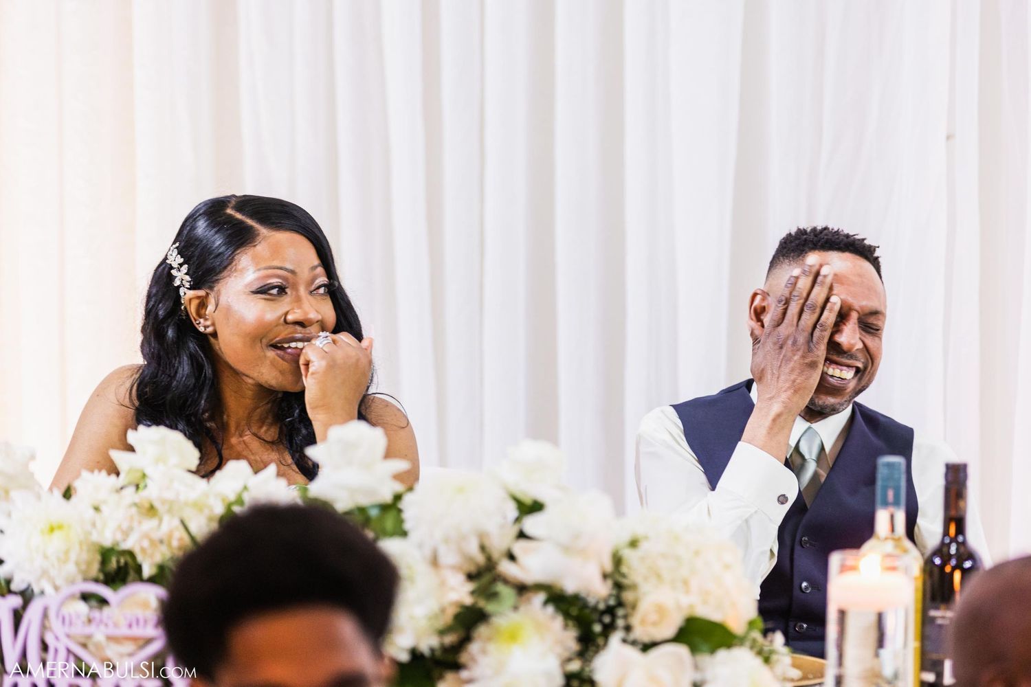 A person in a green dress delivers a speech at an elegant wedding reception.
